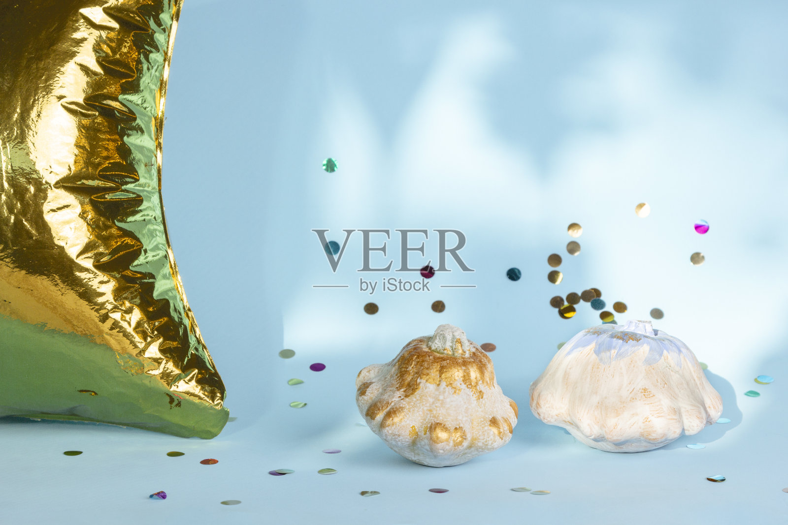 万圣节装饰用白色的南瓜，金色的气球和彩色的纸屑在蓝色的背景。感恩节作文对现代秋季风格。时尚节日的概念。照片摄影图片