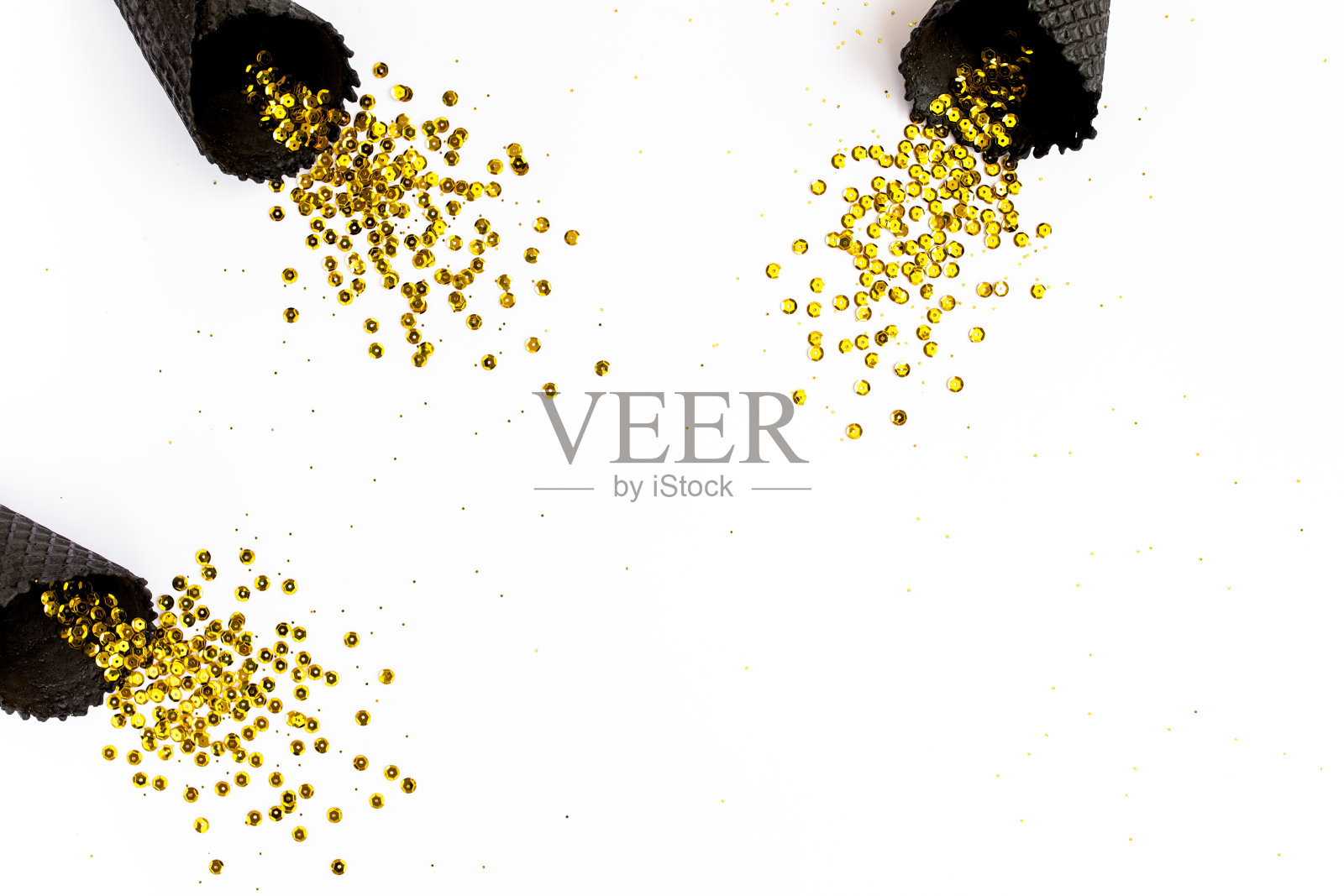 黑色的华夫蛋筒，金色的纸屑点缀在白色的背景上。平铺，俯视图，简约喜庆的概念照片摄影图片