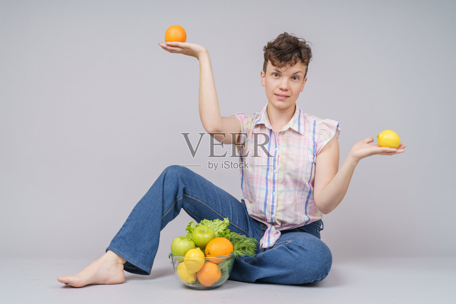漂亮女人用健康的食物，水果蔬菜在盘子里，孤立在灰色照片摄影图片