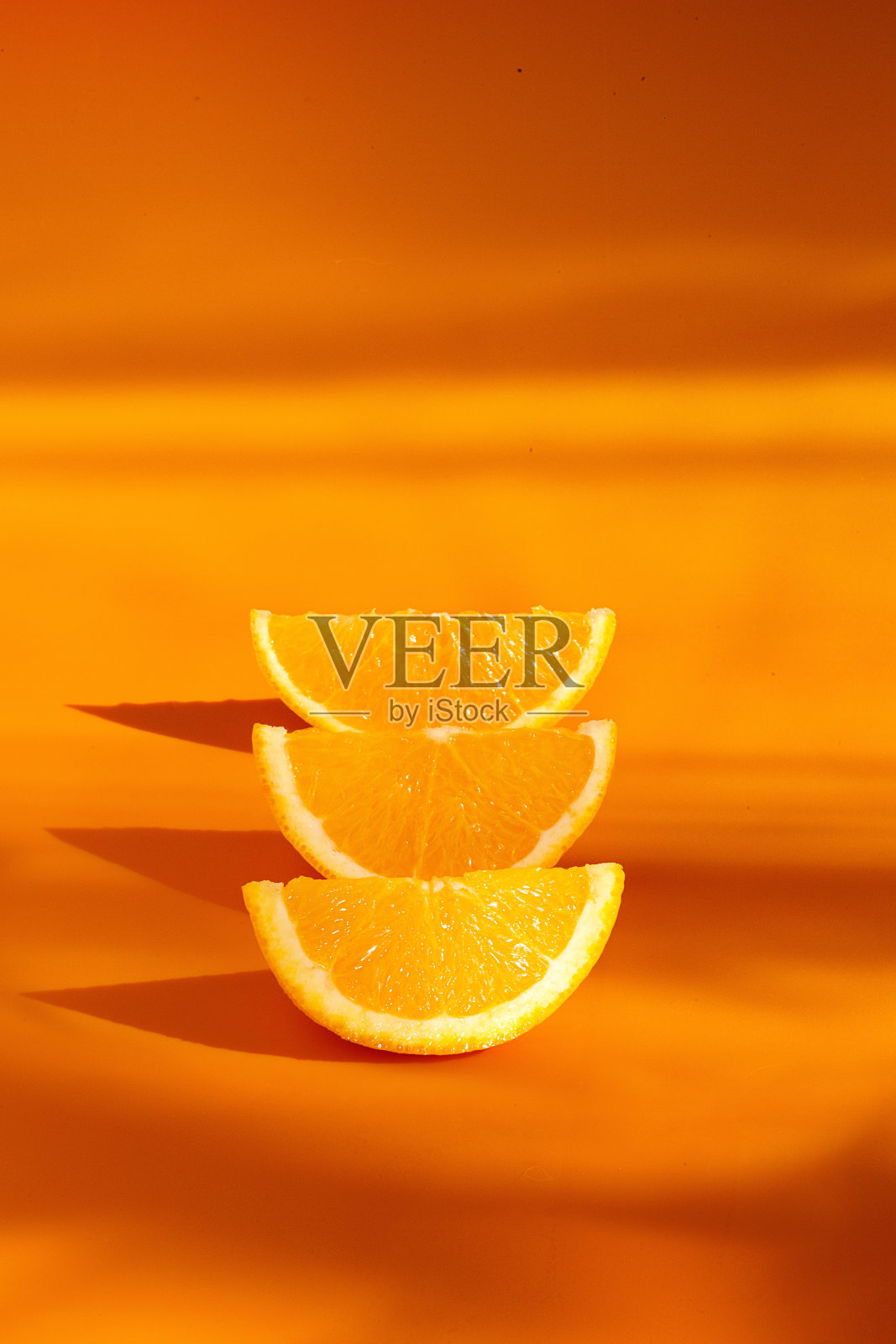 三个橙色的部分在橙色的背景和坚硬的阴影排成一行照片摄影图片