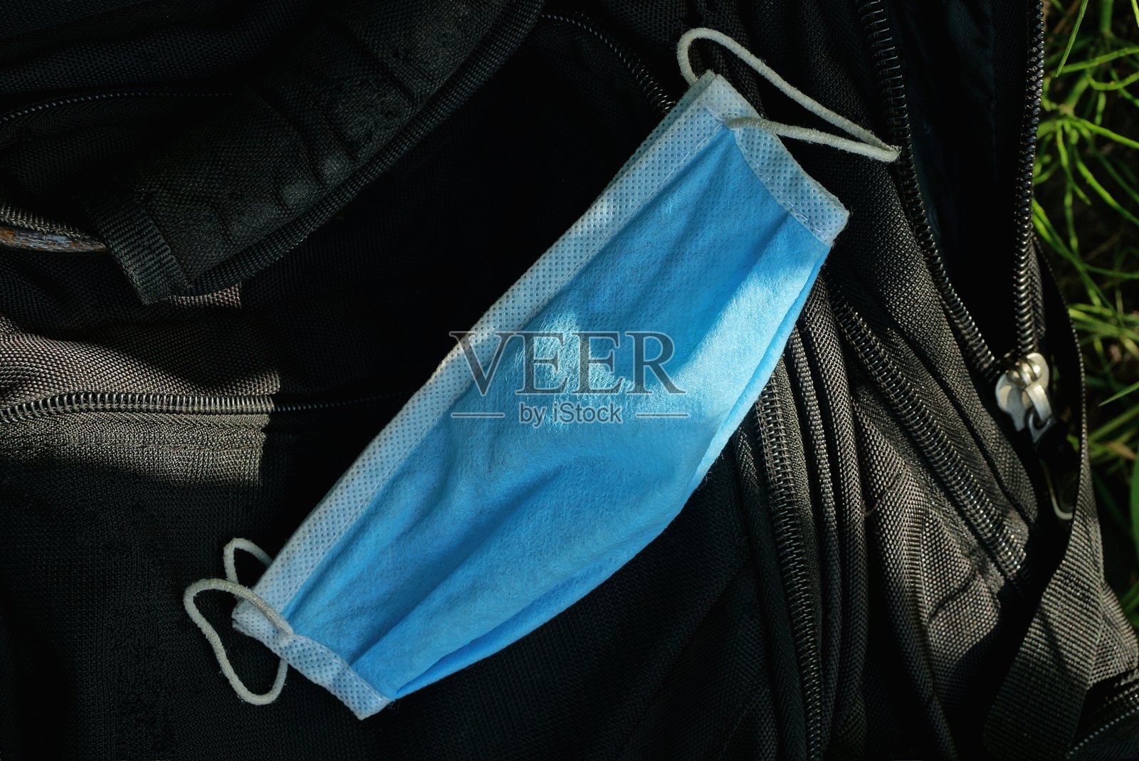 一个蓝色的医用口罩躺在黑色的织物上照片摄影图片