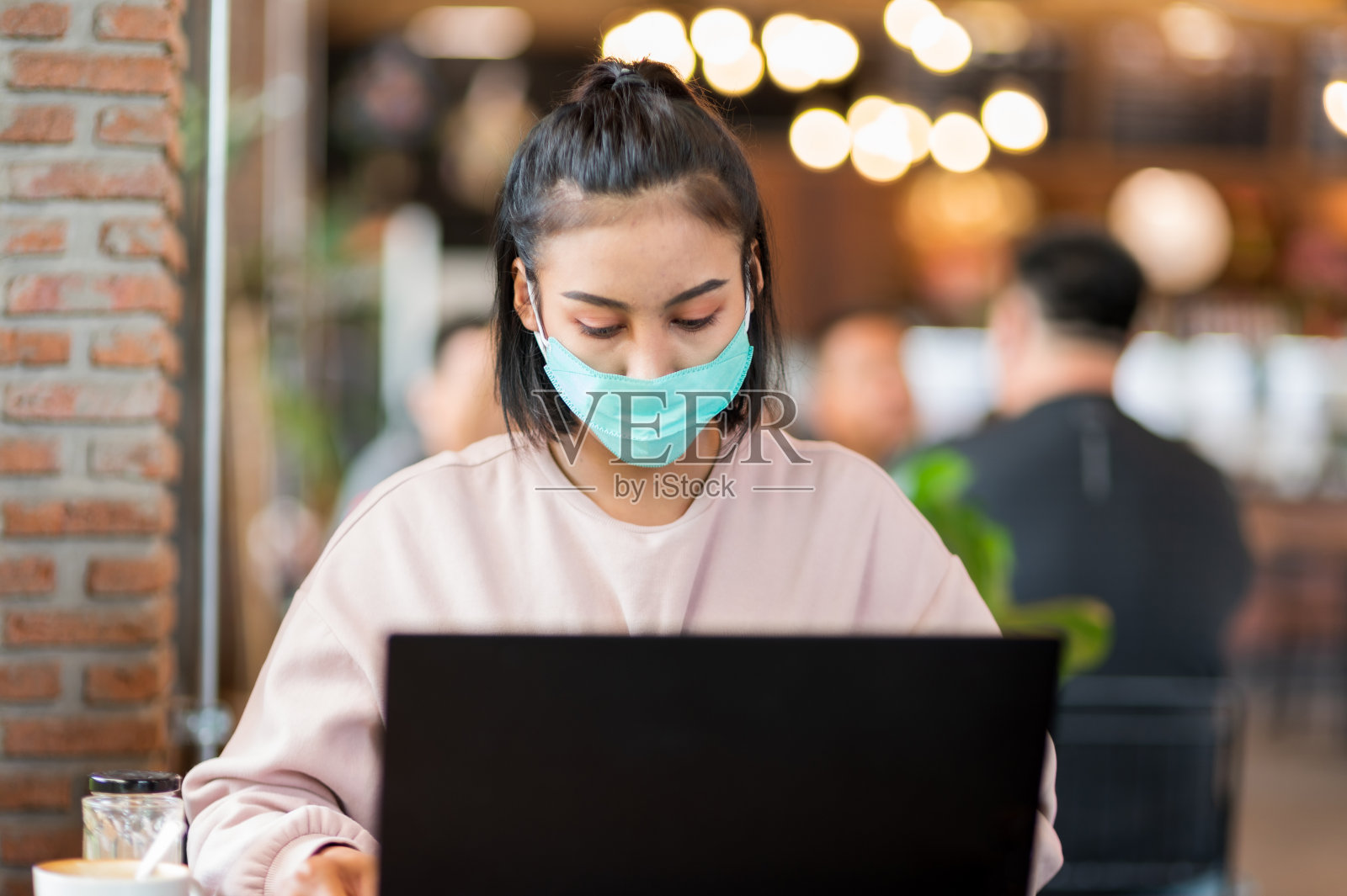 戴着外科口罩的女人在咖啡馆用笔记本电脑网上购物照片摄影图片
