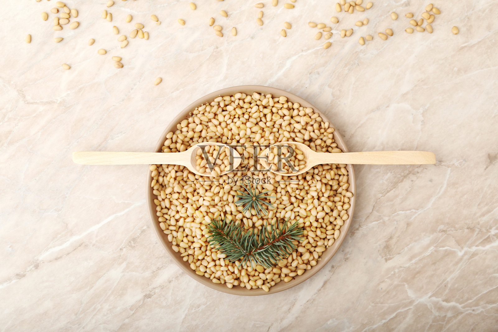 盘子里放松子，两勺雪松早午餐。微笑的脸。俯视图上的米色大理石桌子。食品的概念。照片摄影图片