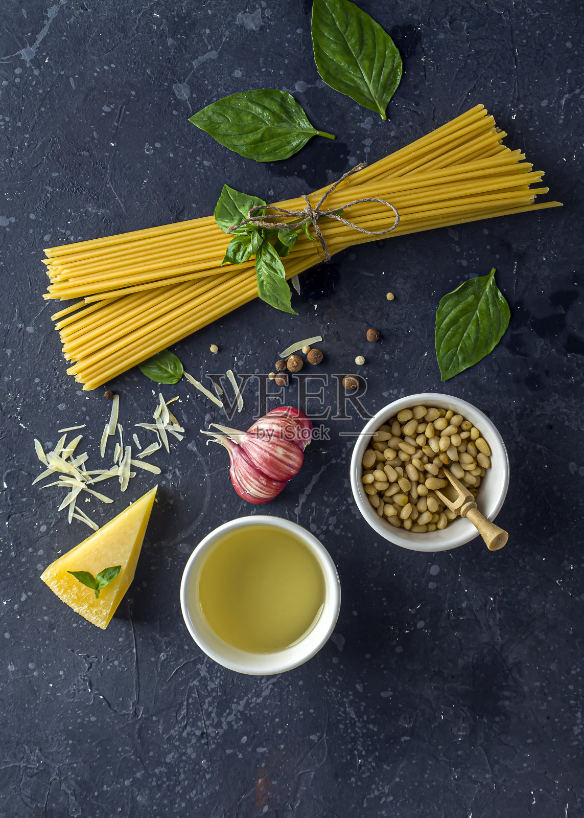 新鲜的食材与传统的意大利酱香蒜沙司。干意大利面，罗勒叶，番茄，帕尔马干酪在深色背景。为文本复制空间照片摄影图片