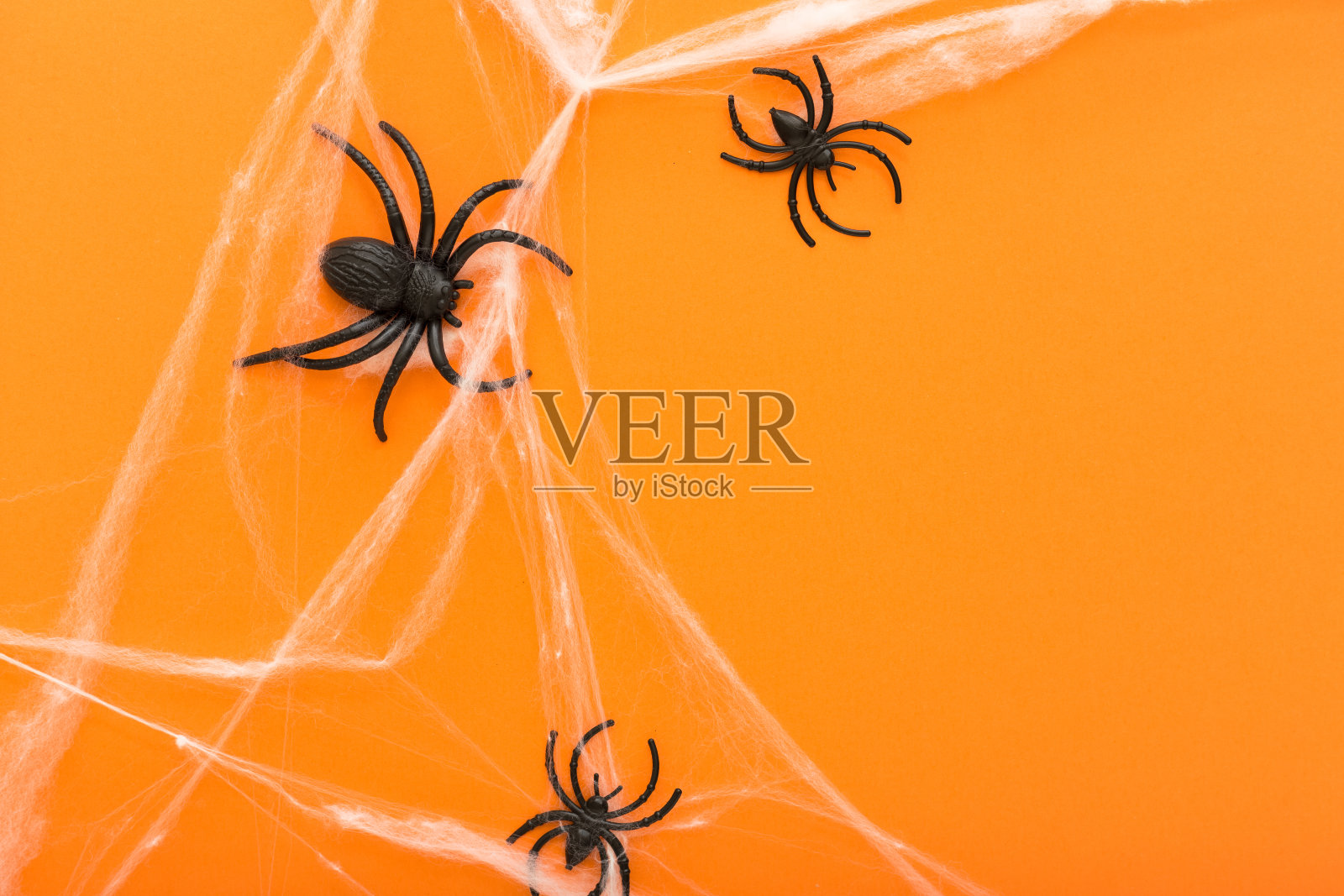 万圣节背景以蜘蛛网和蜘蛛作为万圣节的象征，在橙色的背景上。万圣节快乐的概念。框架。副本的空间。照片摄影图片