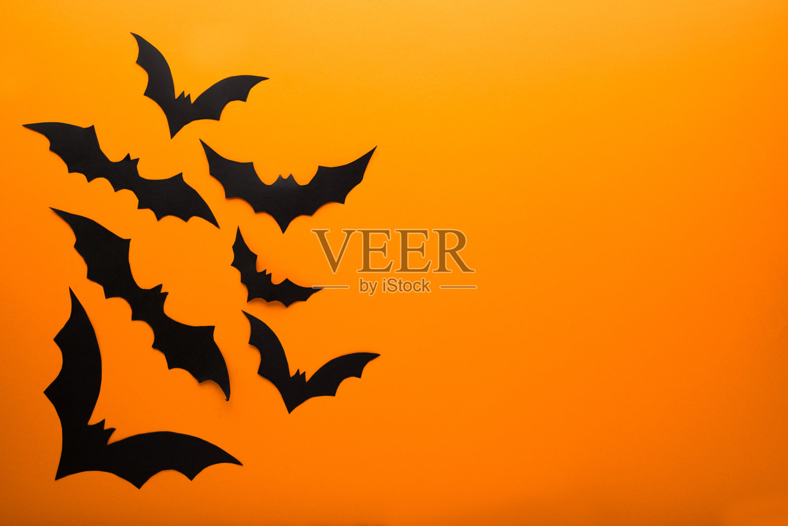万圣节装饰概念-黑色的纸蝙蝠飞过橙色的背景。副本的空间。照片摄影图片