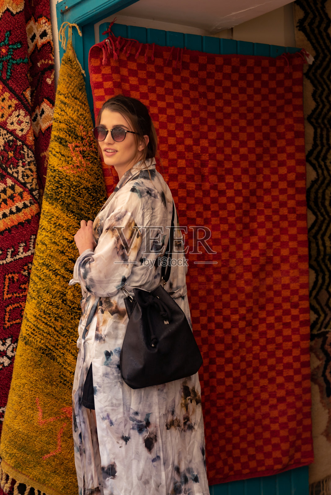 女性游客探索当地文化。欣赏地毯的模式照片摄影图片