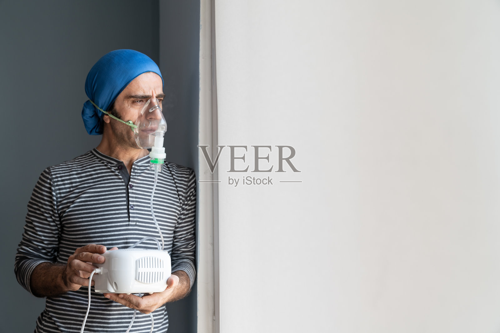 中年男人使用雾化器并望向窗外照片摄影图片