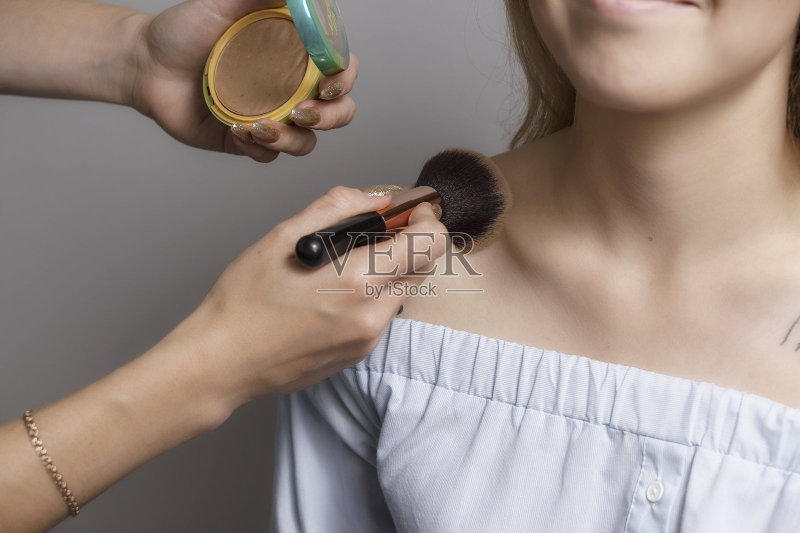 化妆师把粉涂在模特的胸部和肩部照片摄影图片