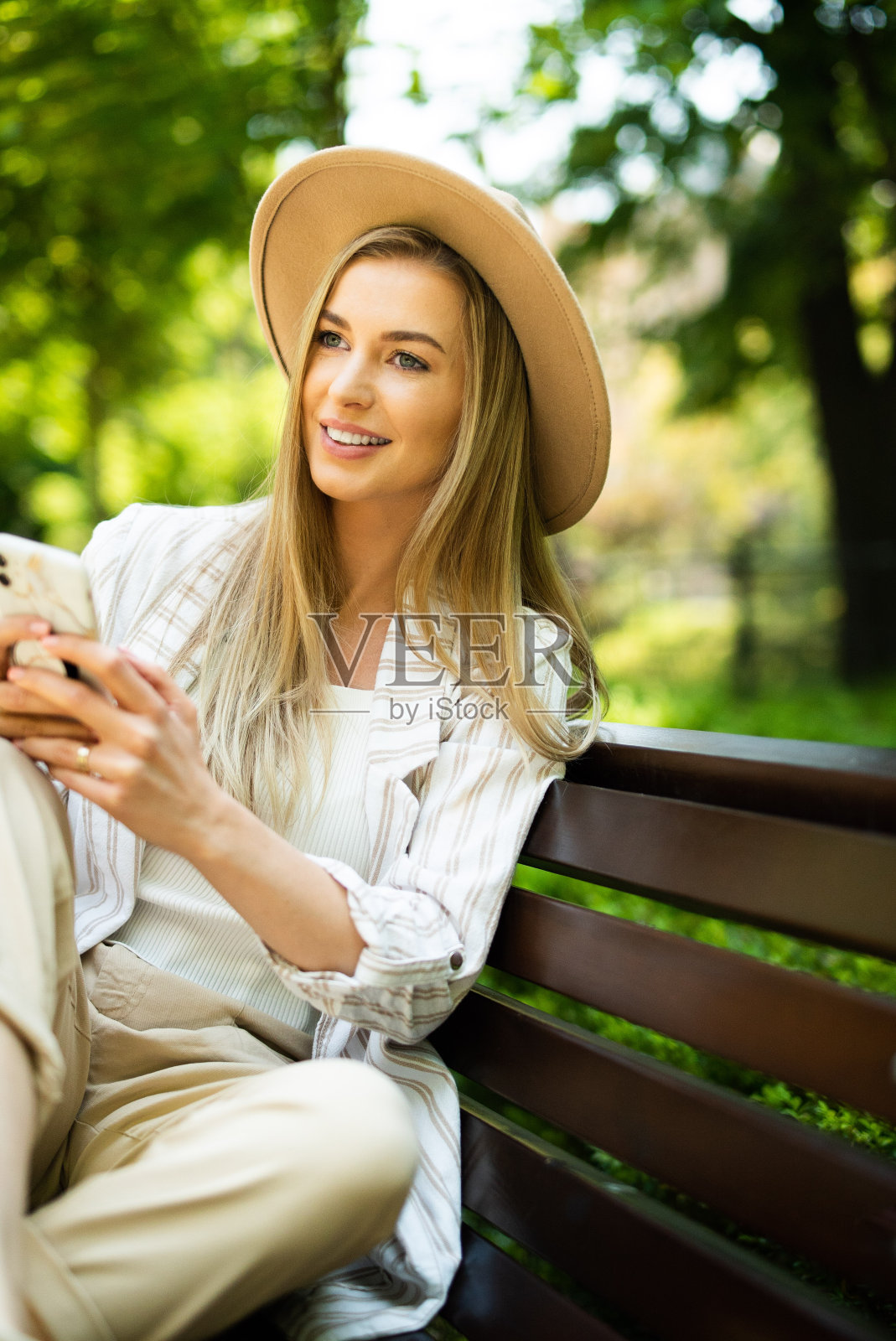 年轻的金发女人在城市公园打电话。照片摄影图片