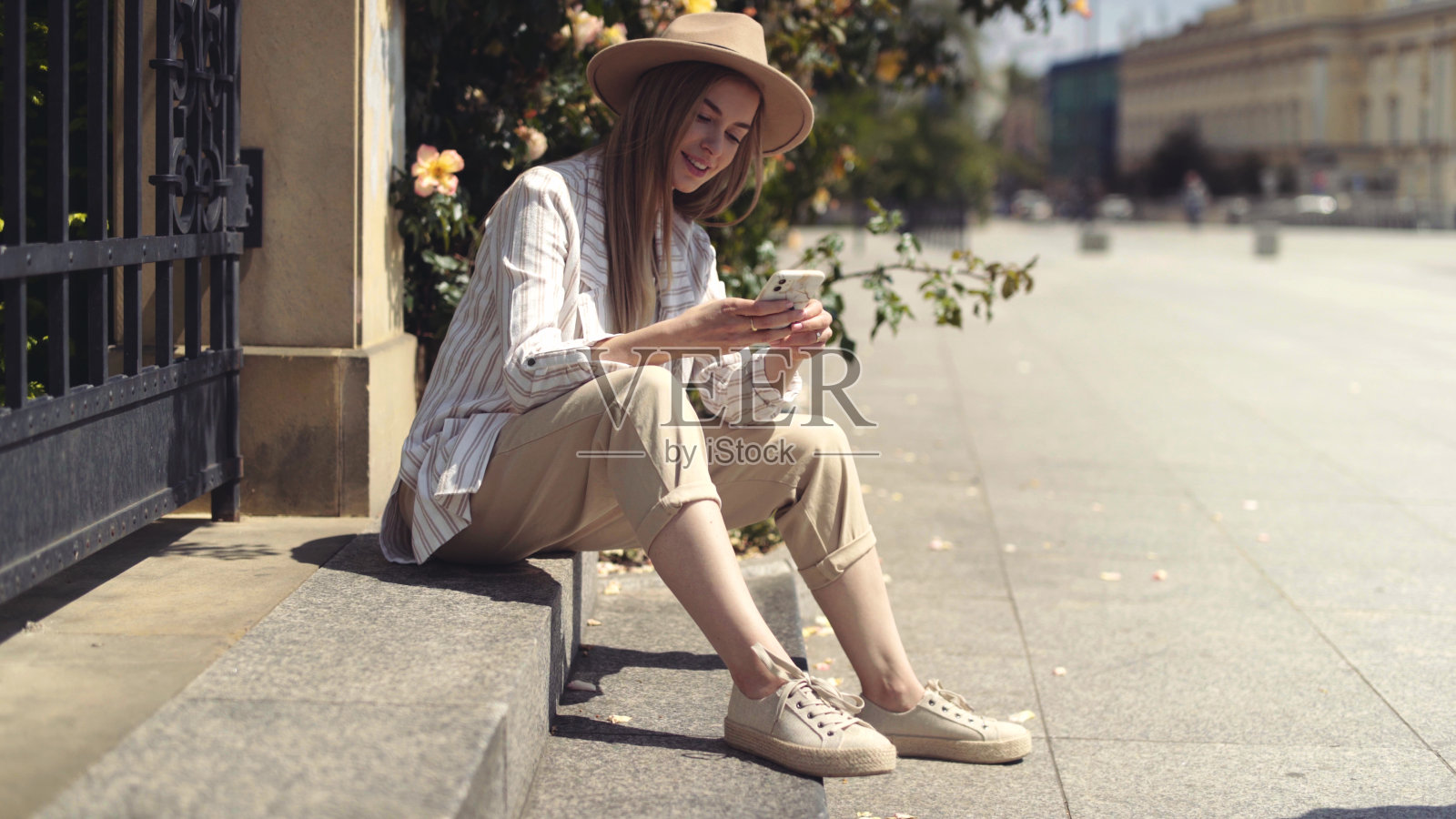 年轻的金发女子在城市公园打电话。照片摄影图片