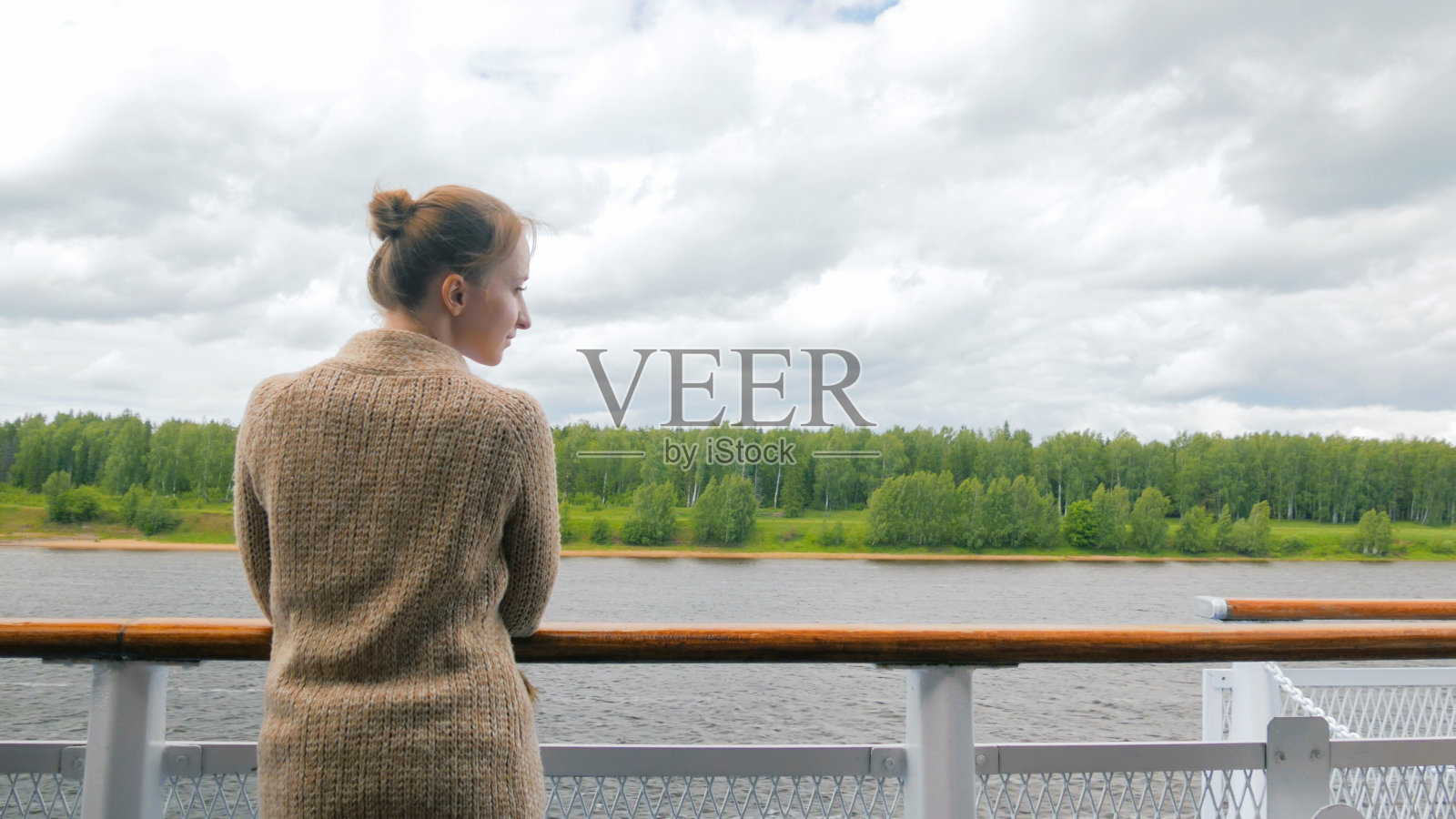 一个年轻女子站在游轮的甲板上看着河照片摄影图片