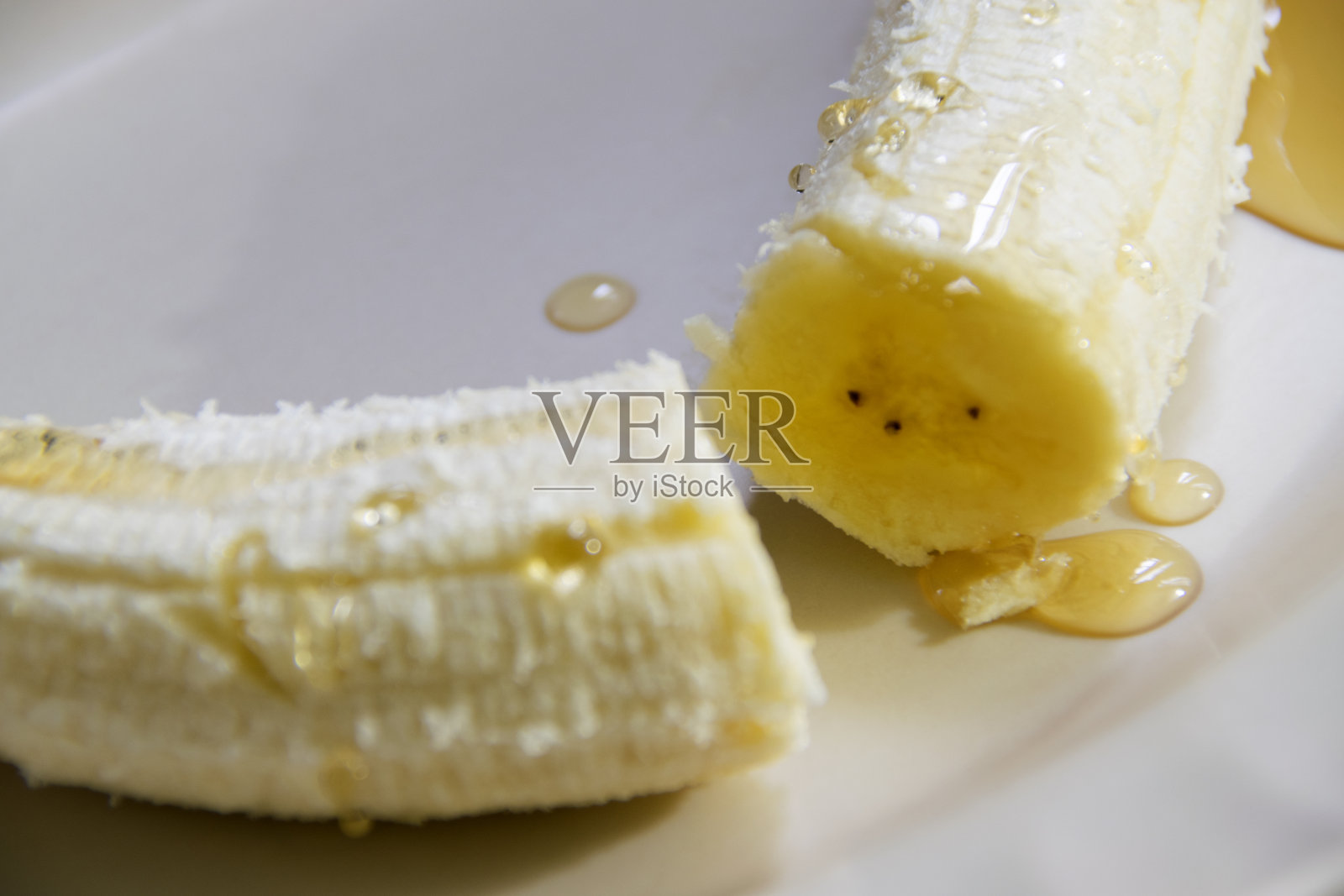 香蕉去皮，盛在盘子里，上面覆盖新鲜蜂蜜、有机产品、营养，以加强防御和预防COVD 29或冠状病毒。照片摄影图片