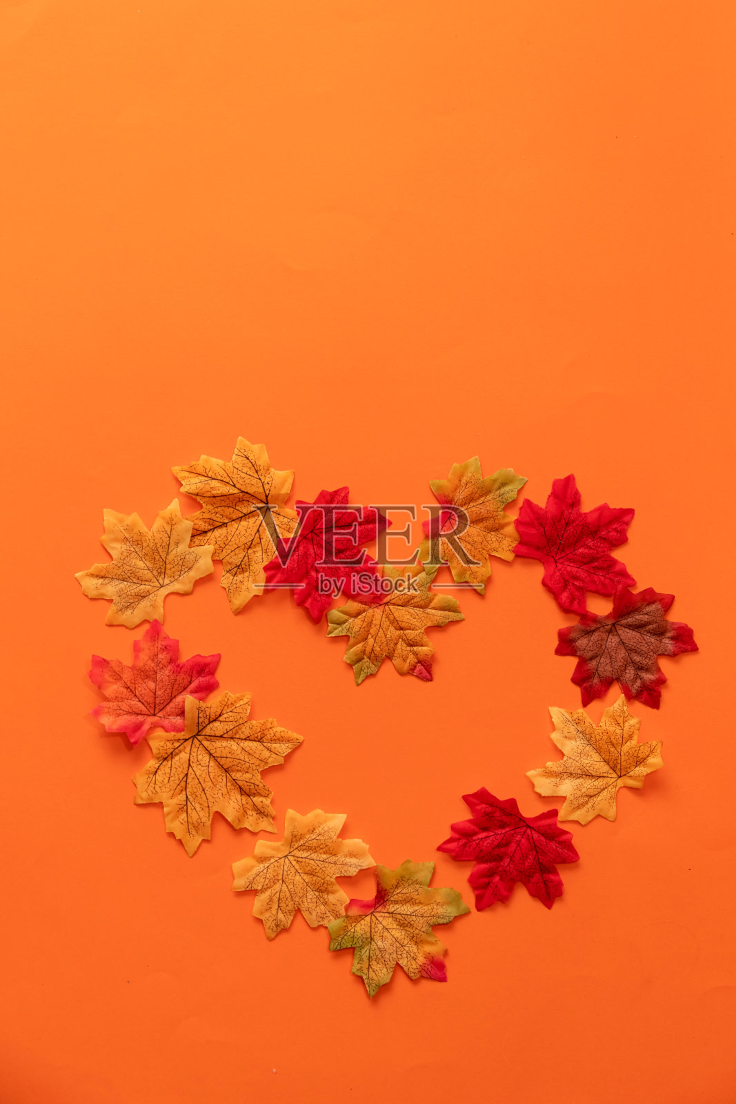 橙色背景上的秋叶做成的心照片摄影图片