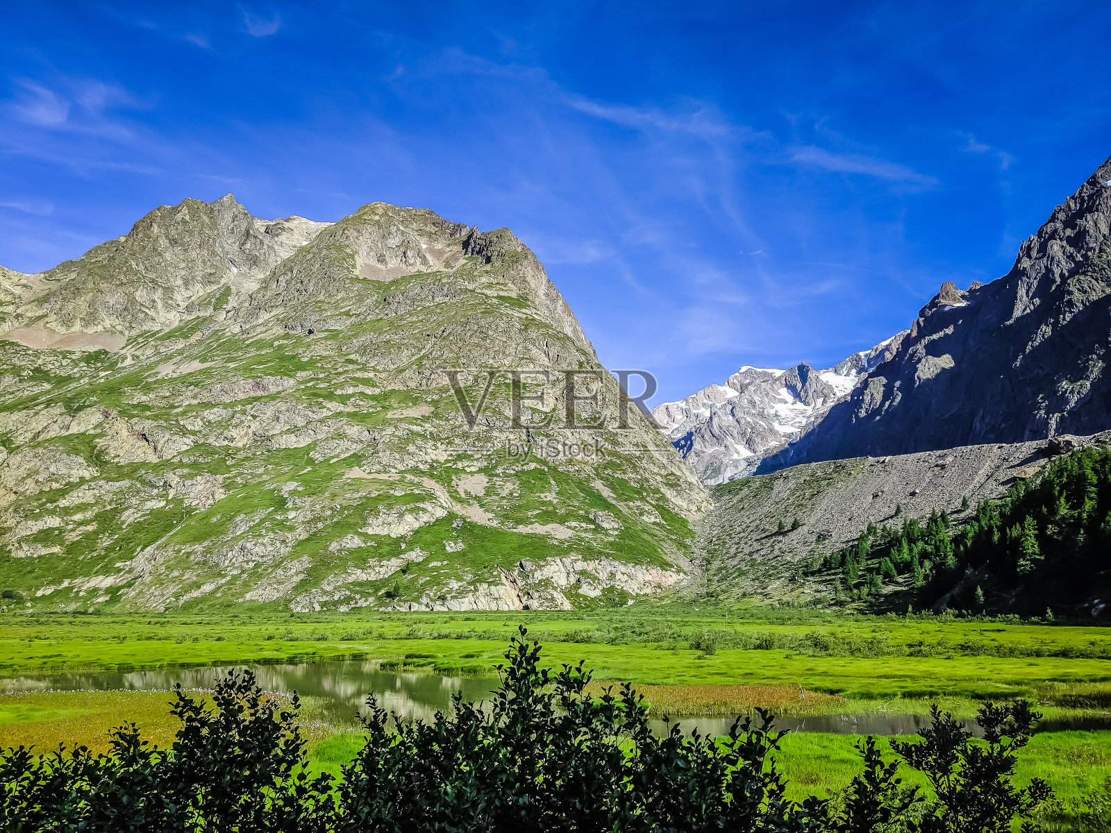 长满草的山脉，有岩石的山丘和积雪。徒步旅行在夏天照片摄影图片