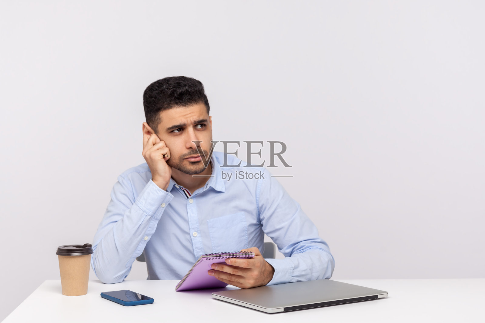 记者或商人在办公室里坐着，拿着纸质笔记本，手托着下巴做白日梦照片摄影图片