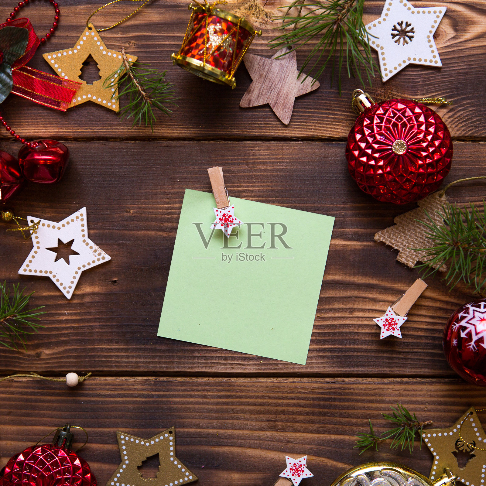 在黑色的背景上，用红色气球、木制星星和晾衣夹铺成的圣诞平铺，中间是一张方形的纸条。照片摄影图片