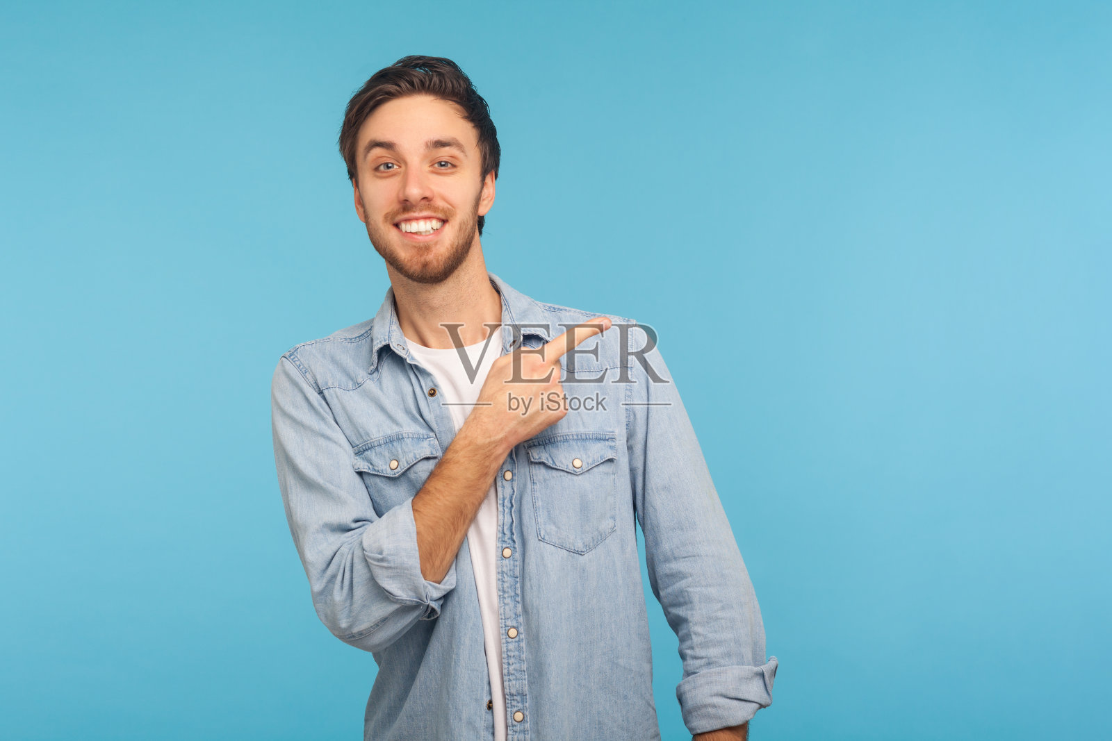 看看这里的广告!肖像英俊快乐的男人在时尚的牛仔衬衫指向一边，显示拷贝空间照片摄影图片