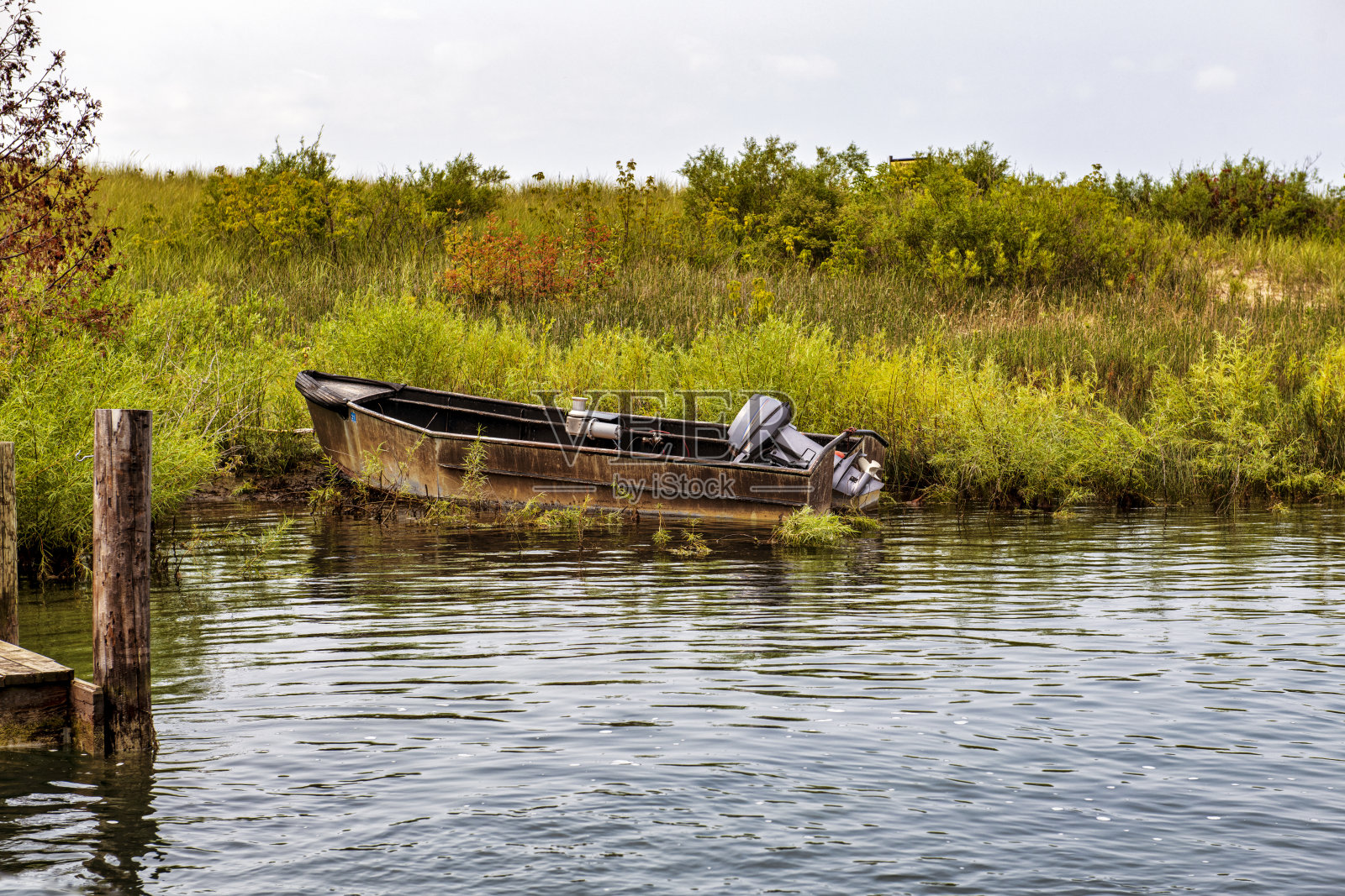 长满草的岸边的生锈的船照片摄影图片