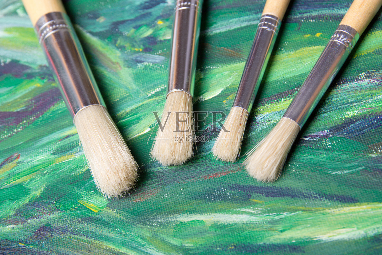 在绿色画布背景上的画笔的特写照片摄影图片