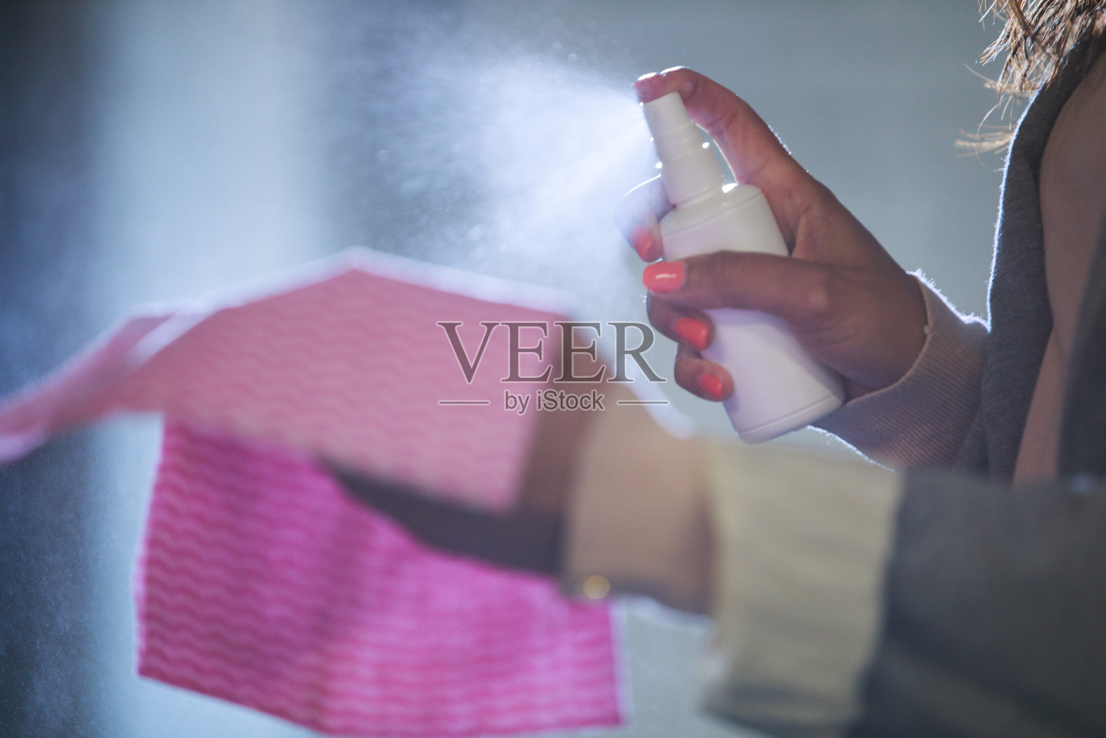 年轻女子在抹布上喷洒消毒喷雾照片摄影图片