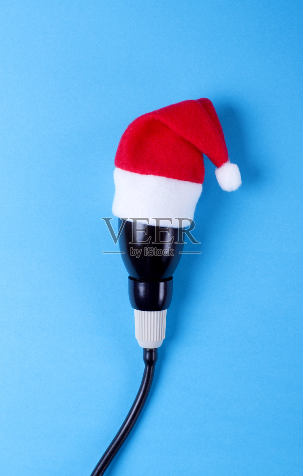 蓝色背景下圣诞老人帽子上的血压计灯泡。为医院检查提供圣诞节特别优惠的概念照片摄影图片
