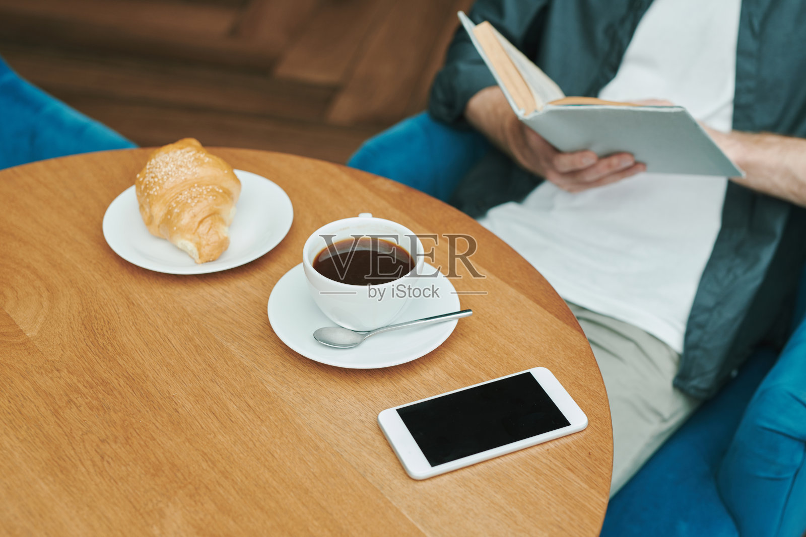 忙碌的年轻胡子男子坐在桌子在现代咖啡馆和喝咖啡，而讨论项目通过电话照片摄影图片