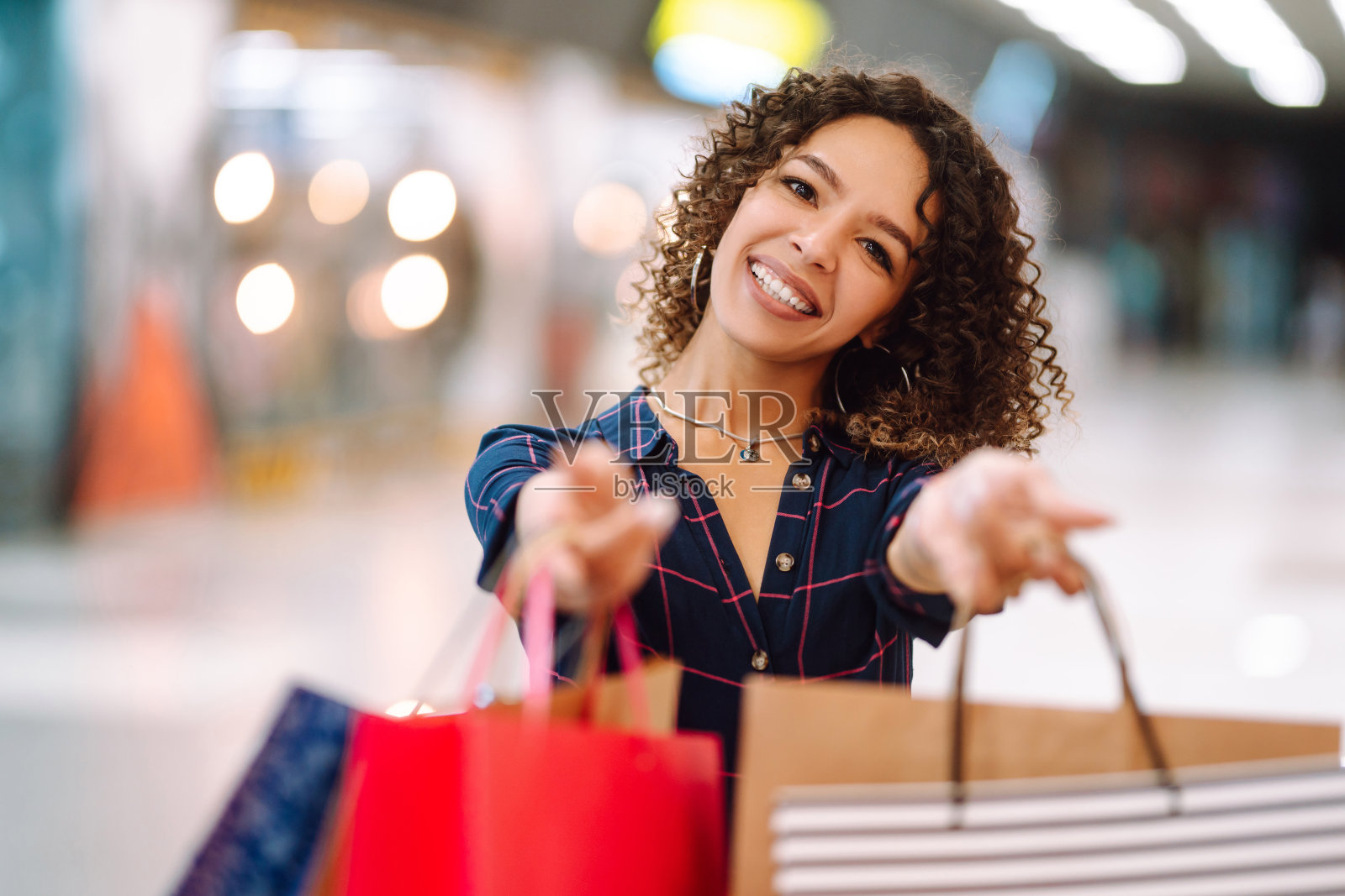 微笑的女人与购物袋享受购物在商场。照片摄影图片