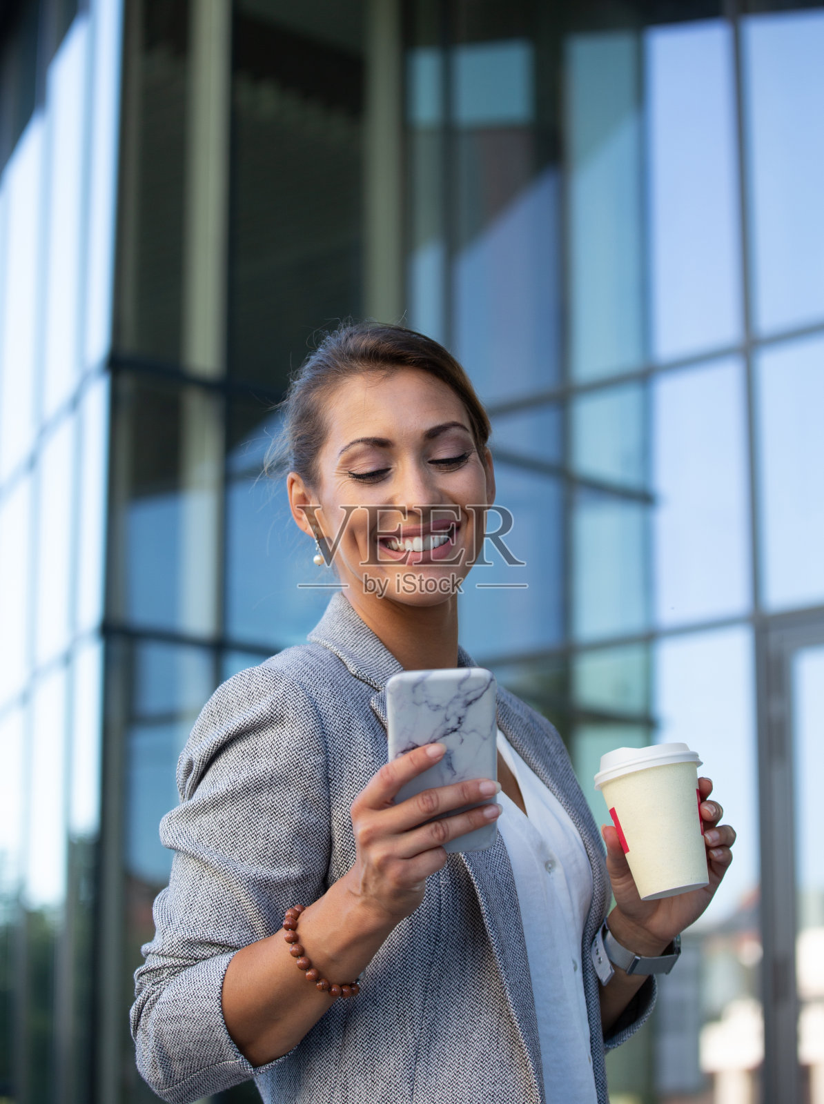 商务女性喝着咖啡，在户外用手机发短信照片摄影图片