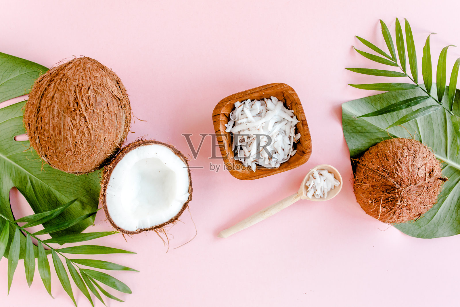 图案与椰子和热带棕榈叶在粉红色的背景。热带抽象背景。平躺，俯视图照片摄影图片