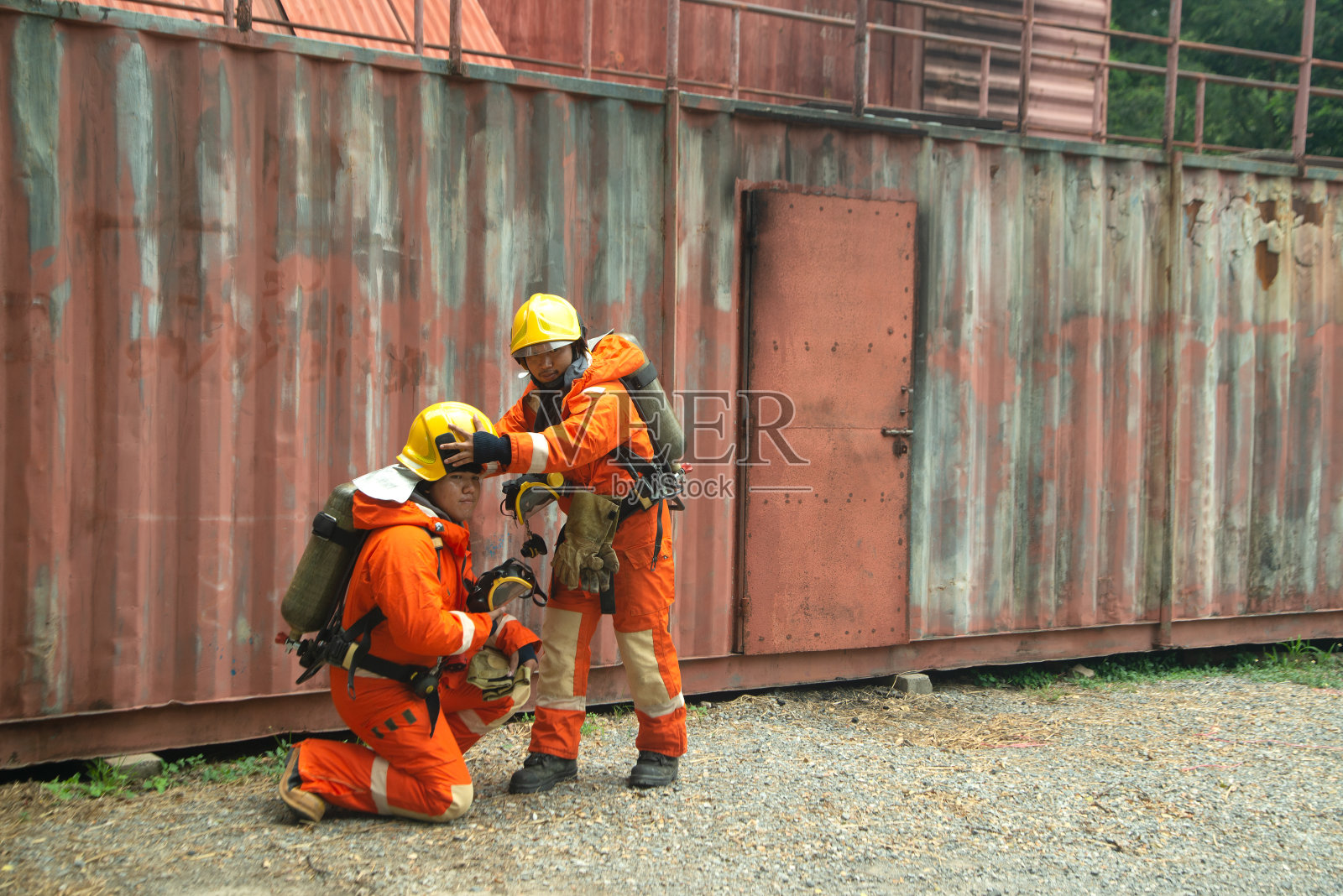 亚洲消防员的肖像穿着橙色的消防制服面具和头盔前面的建筑。照片摄影图片