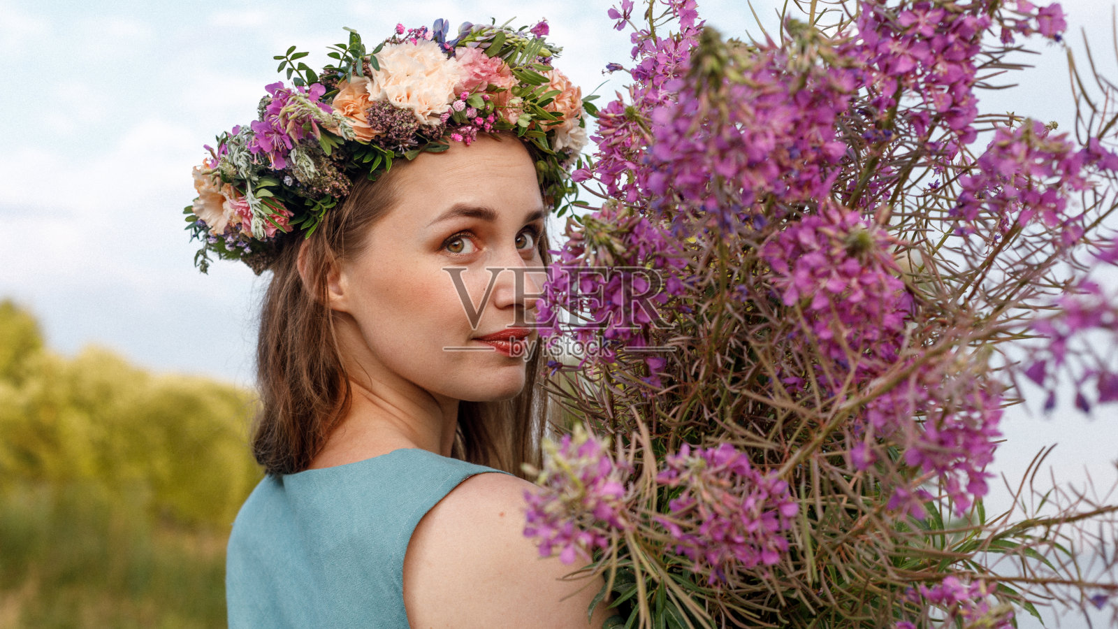 斯拉夫美人，头上戴花圈和一束野花。古代异教起源的庆祝概念。夏至日。中期的夏天。古老的仪式。照片摄影图片