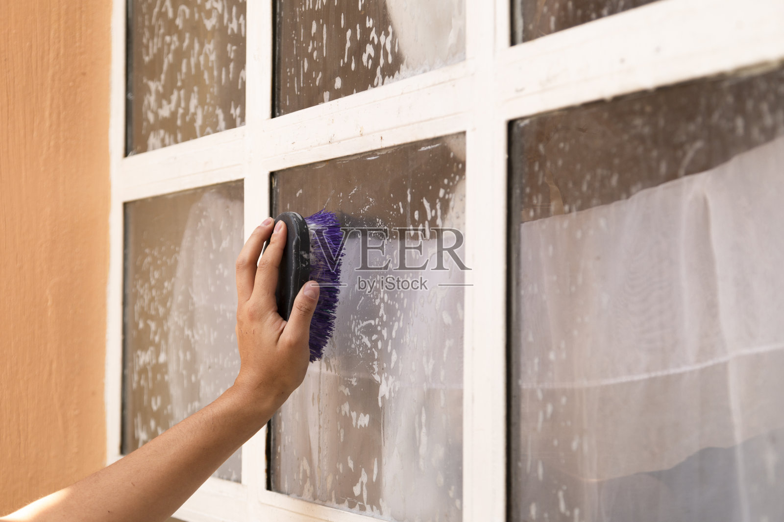 用刷子手用肥皂和水清洗脏窗户-在家里清洁-除尘和玻璃清洗。照片摄影图片