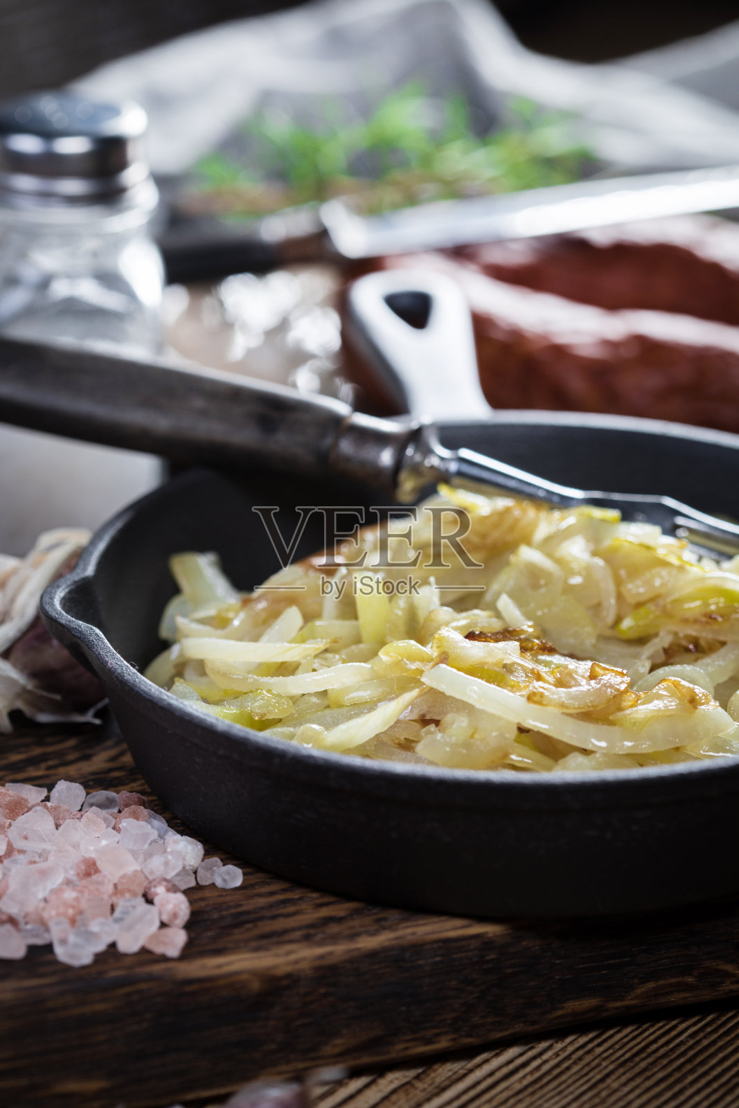 用铸铁煎锅煎洋葱。照片摄影图片