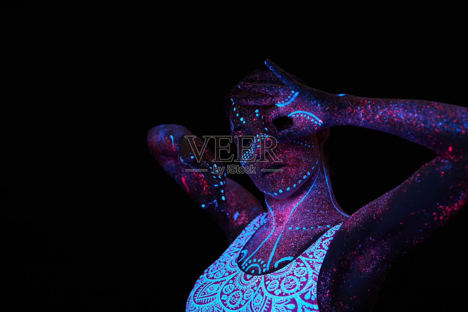 女人做瑜伽，手部运动，热身运动。紫外线下的艺术女孩宇宙。全身覆盖着彩色的水滴。星体瑜伽。噪音，焦点模糊照片摄影图片