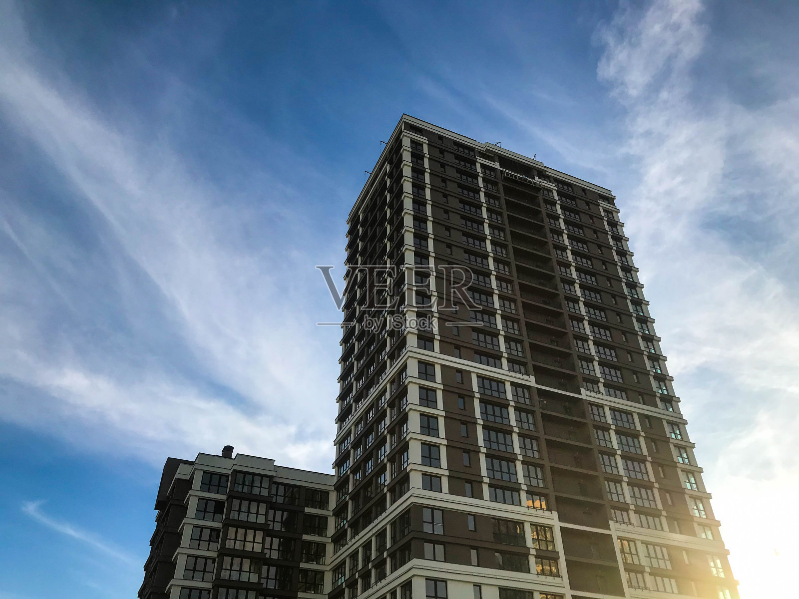 在一个白色和棕色的城市里，一座高大的多层玻璃建筑。以晴朗的蓝天为背景。全景窗户，全新的人体工程学和时尚领域。在阿拉伯风格照片摄影图片