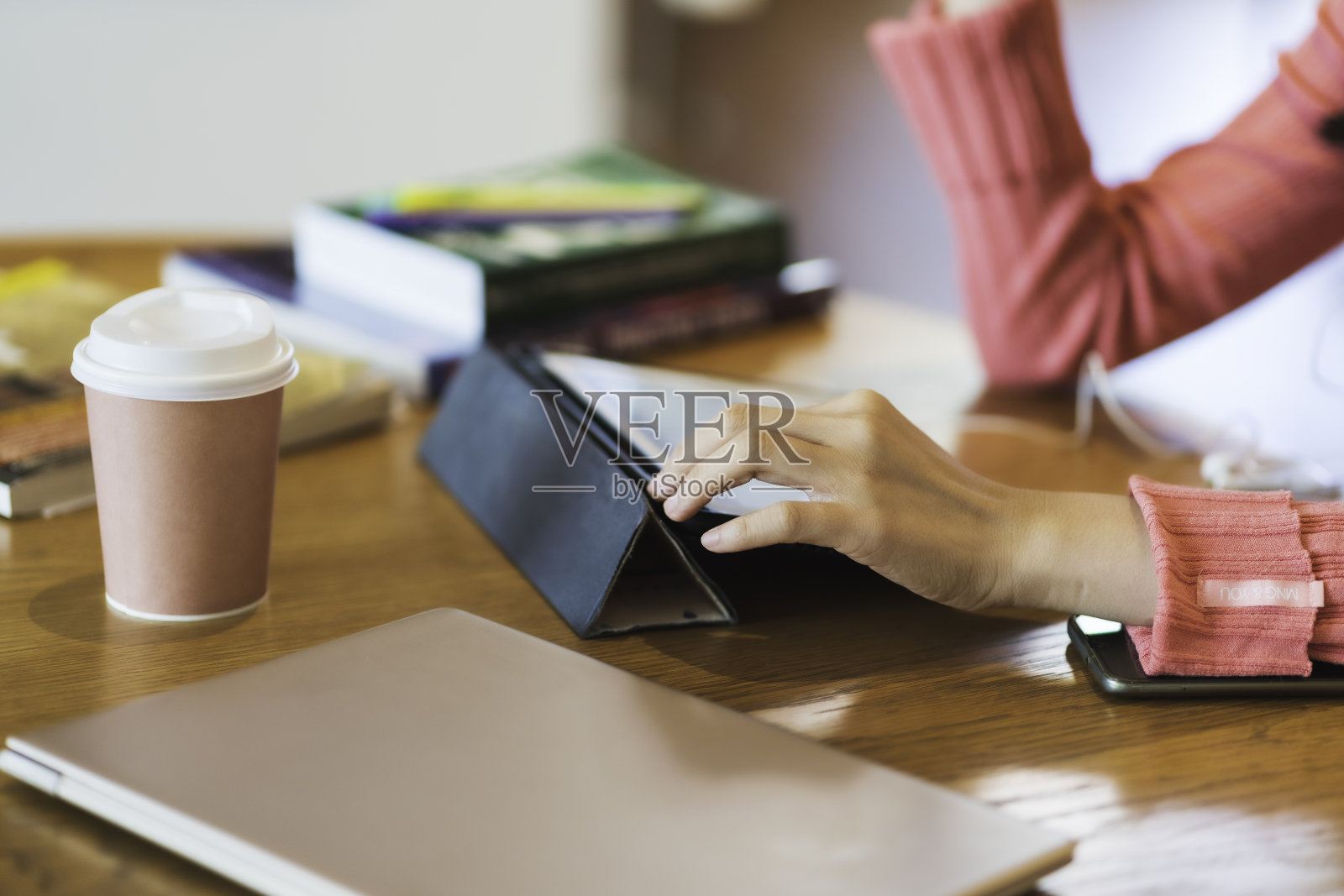 近手的亚洲妇女在粉红色毛衣使用平板电脑在线学习照片摄影图片