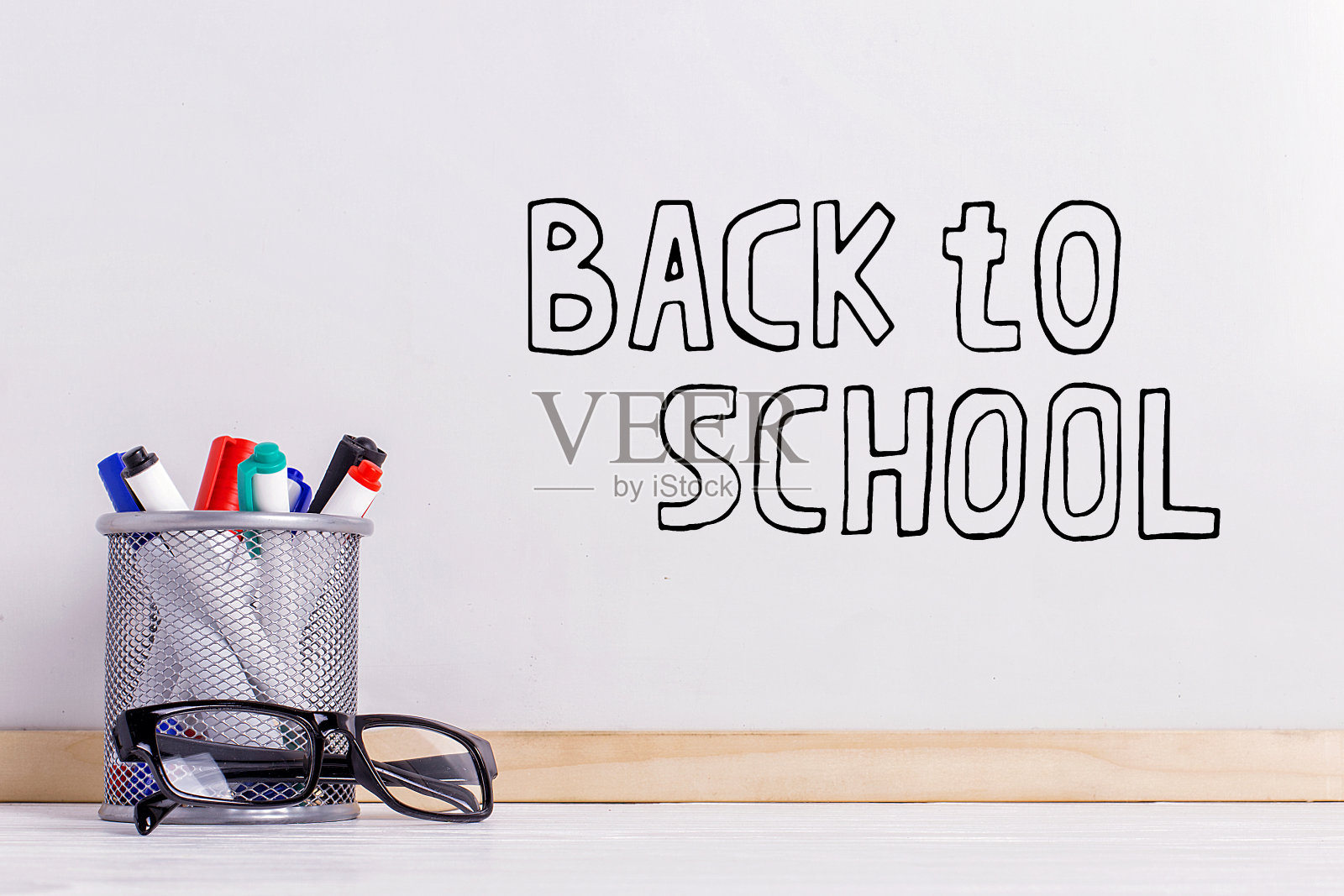 马克笔，眼镜和一块白板。白板上的题词是“回到学校”。照片摄影图片