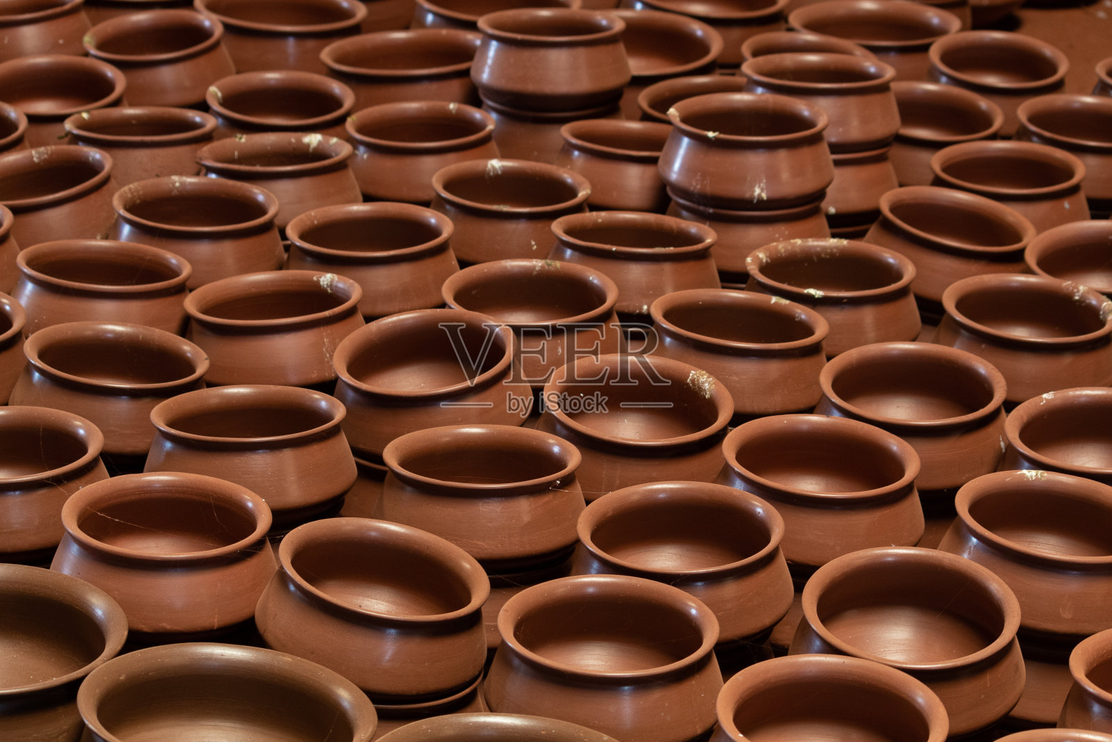 印度古吉拉特邦附近的传统陶器店，一排未烘烤的陶土陶罐。俯视图大而短的古代花盆。生焙陶土陶器全框架背景照片摄影图片