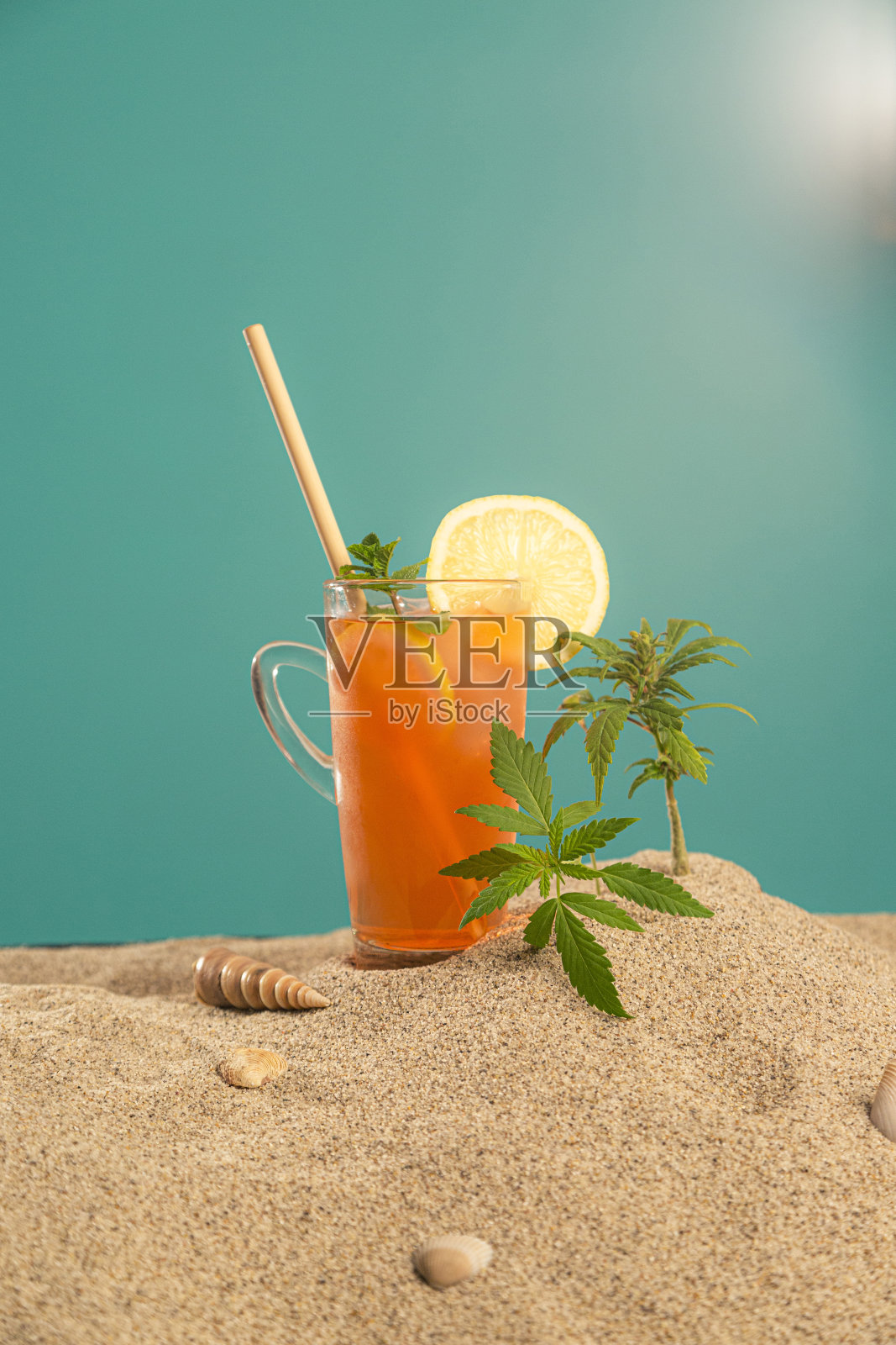 CBDa油，橙汁或冰茶的产品在一个罐子和贝壳在沙子上照片摄影图片