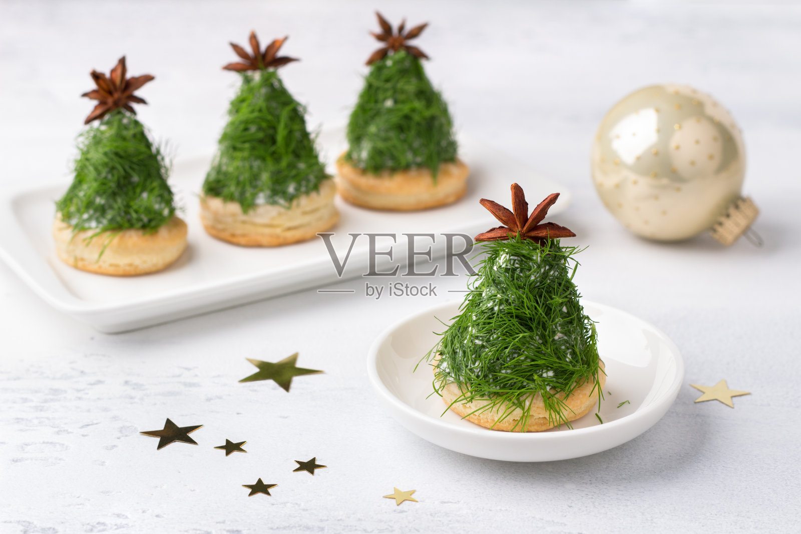 圣诞树形状的圣诞点心。美味的奶油芝士点心配坚果、大蒜和切碎的莳萝，用八角装饰。浅灰色背景照片摄影图片