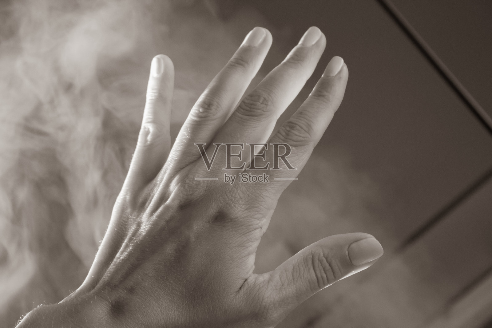 张开手掌，五指在烟中过滤。人的手臂在自然光下有阴影，有色调，有深褐色。帮助的姿态。不透明度的概念。女人的手在薄雾。照片摄影图片