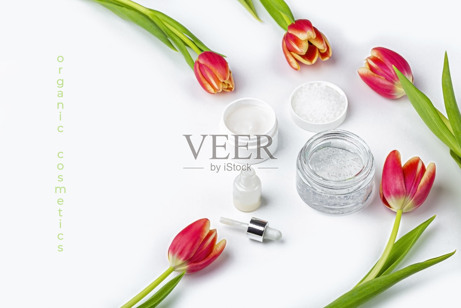 天然有机自制化妆品概念。皮肤护理、治疗和美容产品:在白色背景下的春季红色郁金香花中，装有霜和血清的容器。关闭，为文本复制空间照片摄影图片
