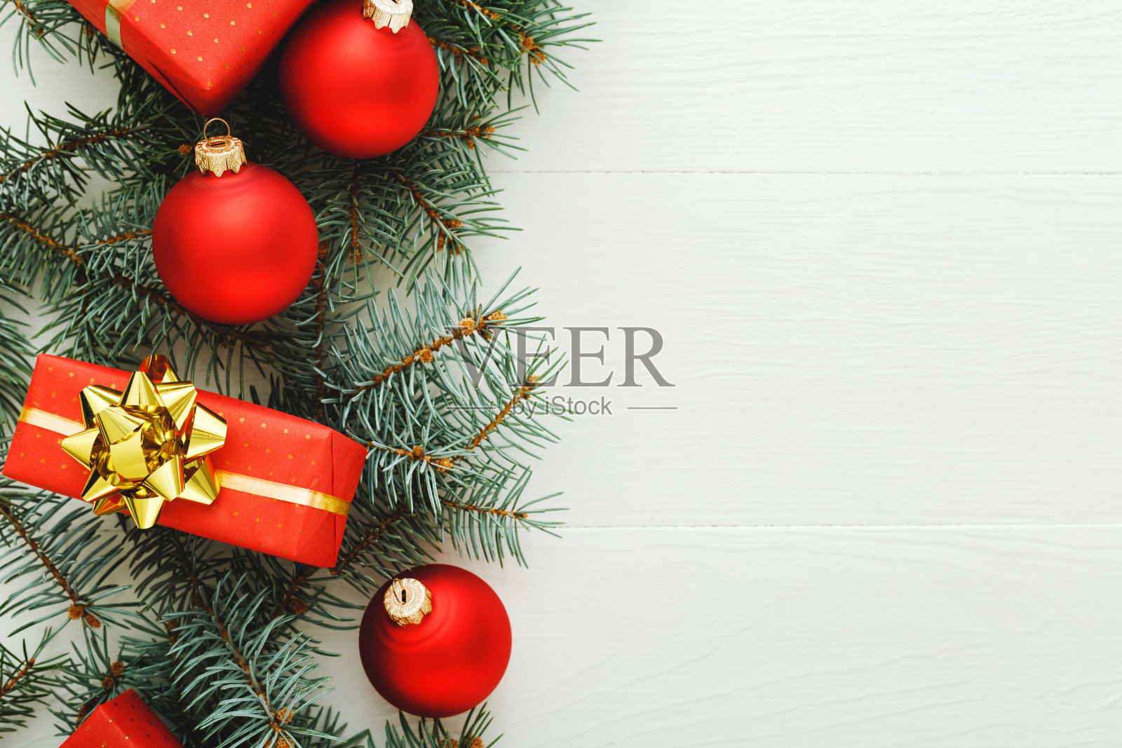 2020年圣诞新年庆祝模式组成的红色礼品盒，杉木树枝，球在白色的木制背景。概念圣诞时间，冬天。平铺，俯视图，拷贝空间照片摄影图片