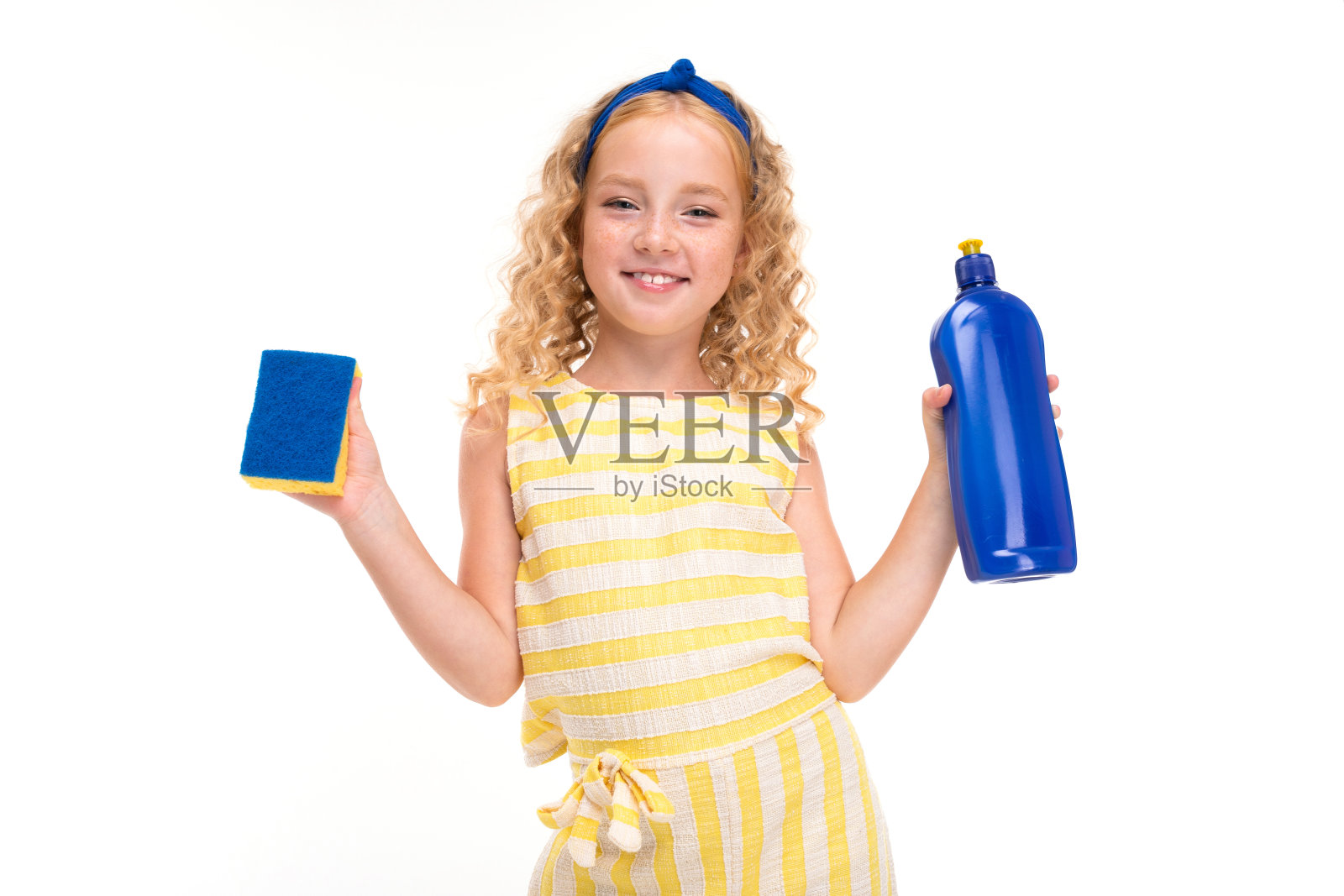 一个快乐的孩子带着一头金黄色的卷发在洗盘子照片摄影图片