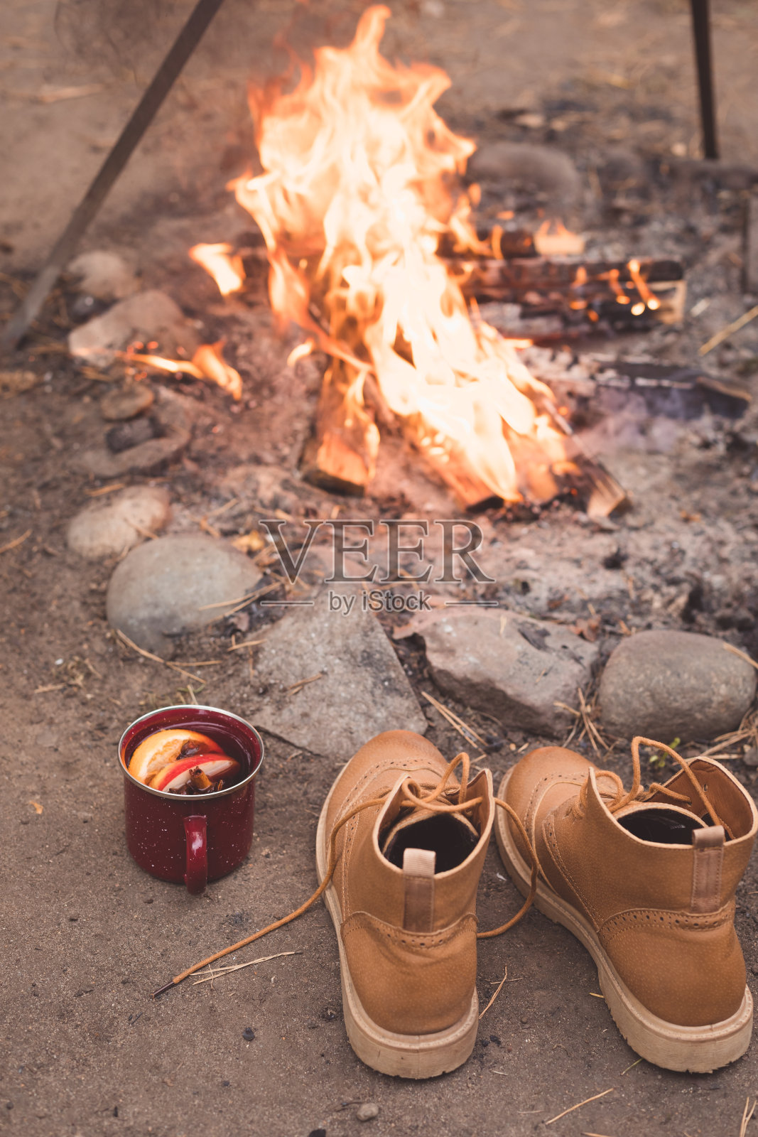 杯里装着辛辣的热红酒，靴子盖过篝火照片摄影图片