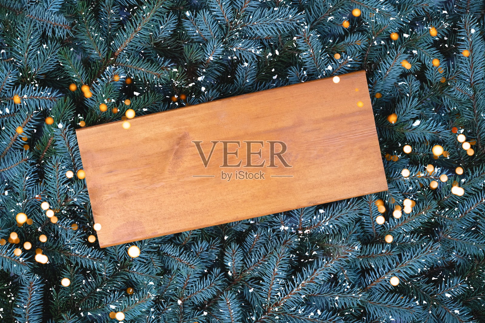 在圣诞树树枝背景上的一块旧木板。照片摄影图片