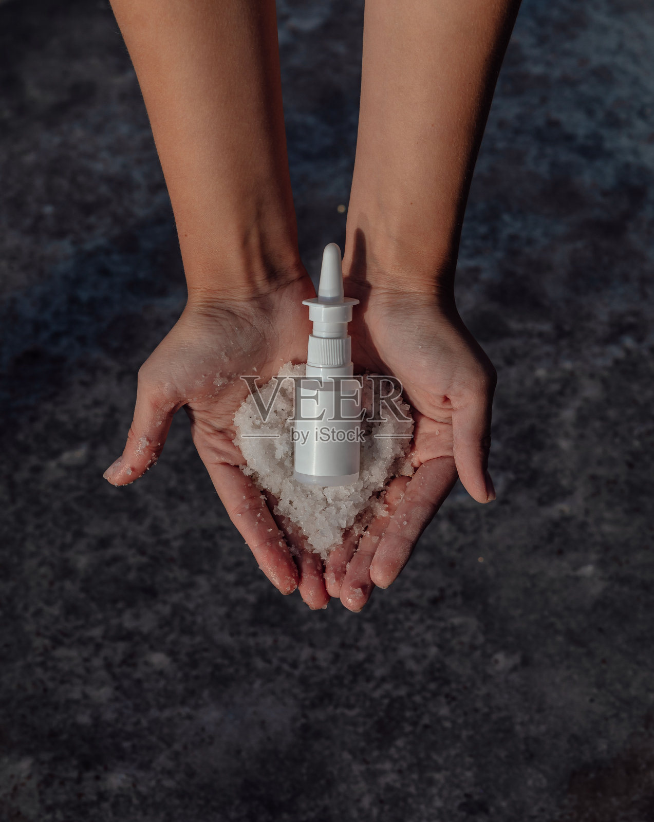 手上拿着盐和一瓶药。通过鼻腔喷雾剂治疗感冒照片摄影图片