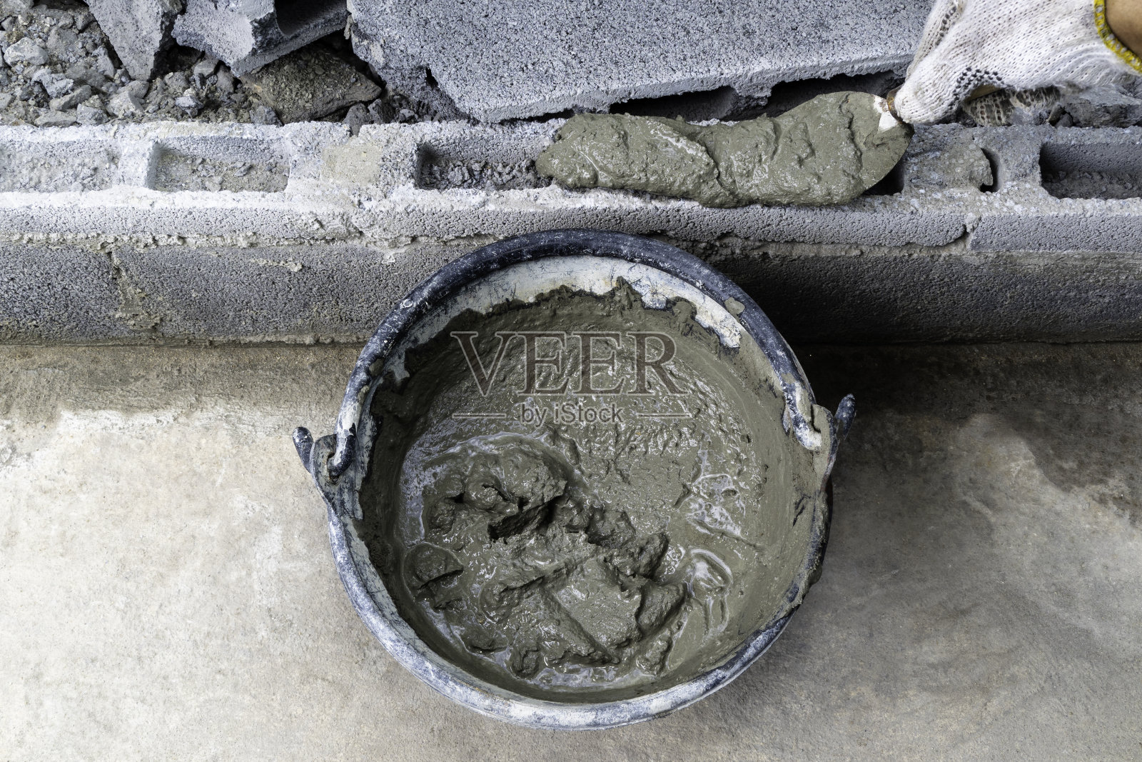 用桶和泥铲上的水泥砌筑。照片摄影图片