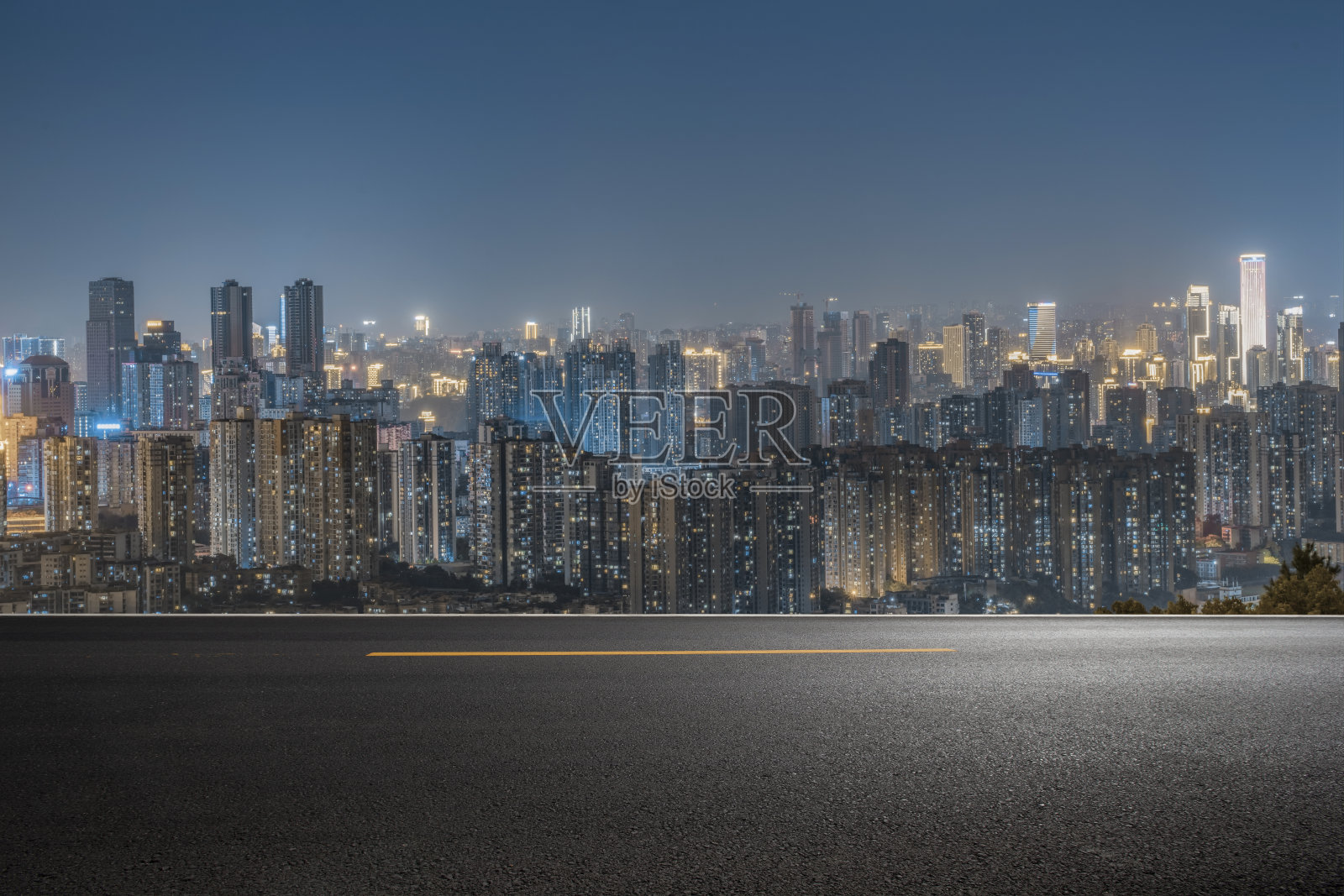 空旷的混凝土地面在市中心与照明的现代城市景观和建筑物在晚上。照片摄影图片